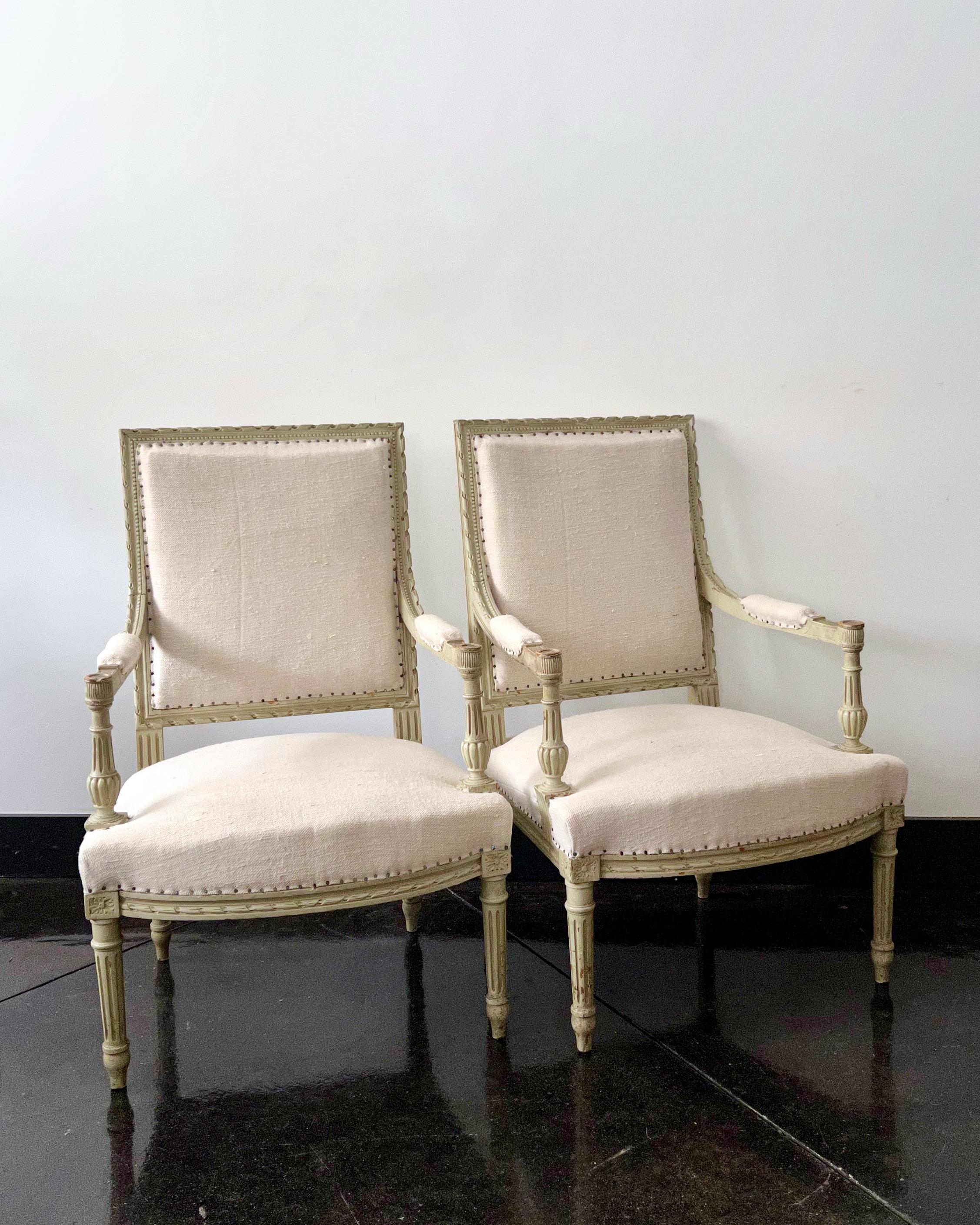 A pair of 19th century French armchairs à la reine with flat back and richly carved armrest with acanthus and rosettes on fluted tapered legs, showing in original worn finish.
Upholstered in raw linen.