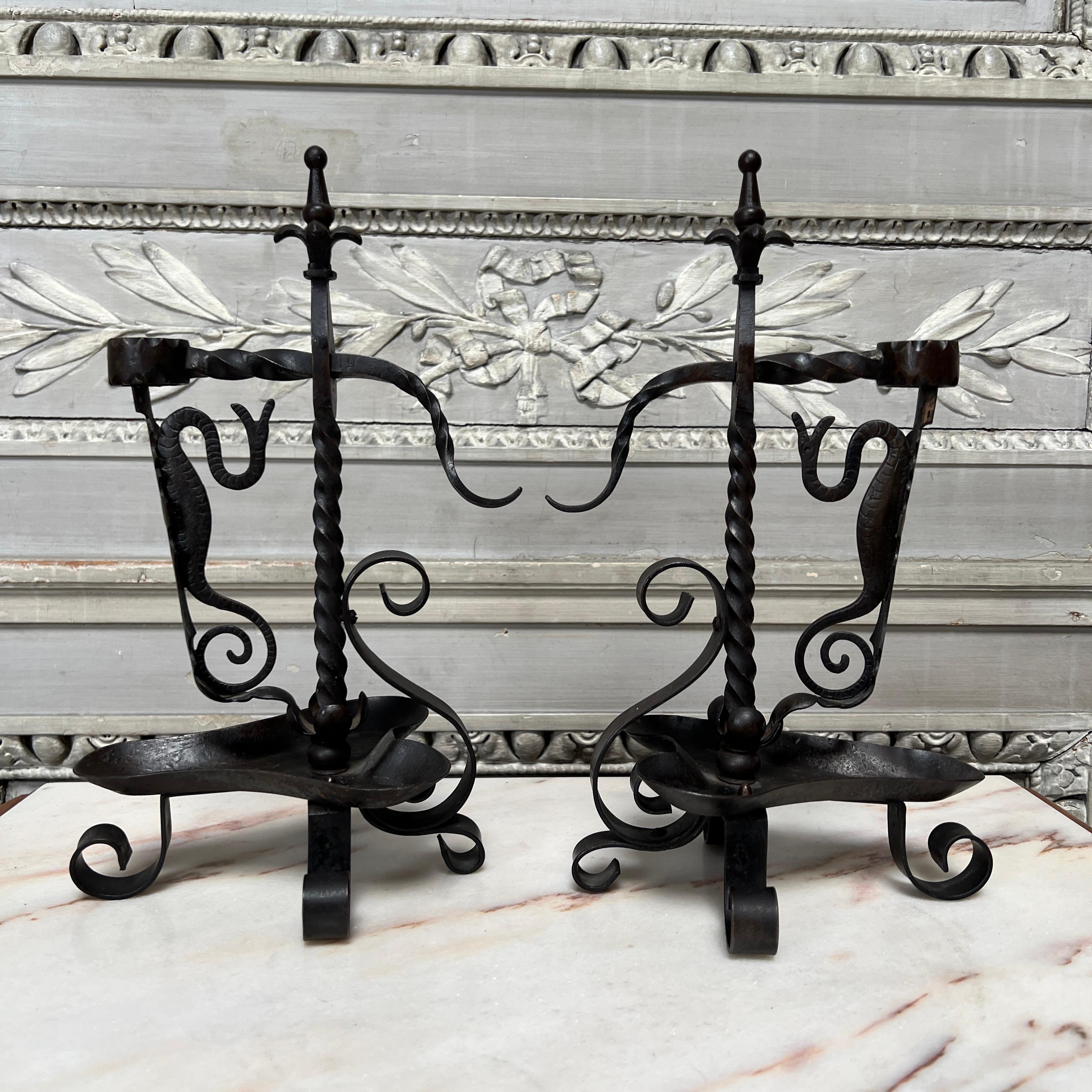 A pair of forged iron candlesticks candle holders with a handle in the form of a sea creature and a movable clamp to keep your candle in place and secure. These unusual candle holders are nicely made and highly decorative.