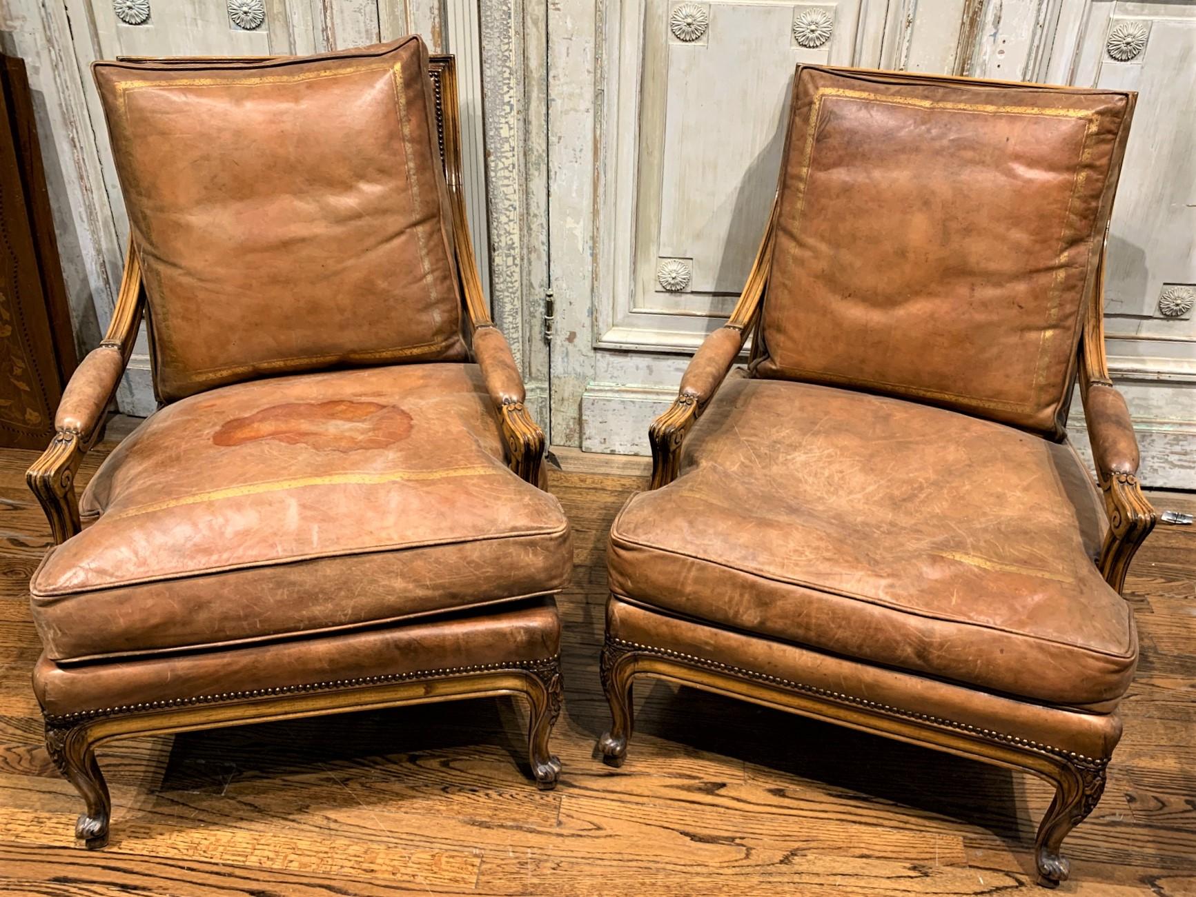 Handsome large scale pair of 19th century French fruitwood and tooled leather fireside chairs featuring nail-head trim, carved knees, and whorl feet;

circa 1890.
