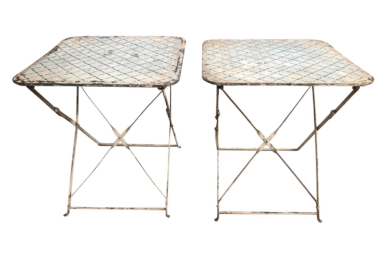 A delightful pair of later 19th century collapsible French garden tables in painted iron. Wonderful motif and painted finish. Perfect end tables for a charming interior or garden, or smaller bedside tables.