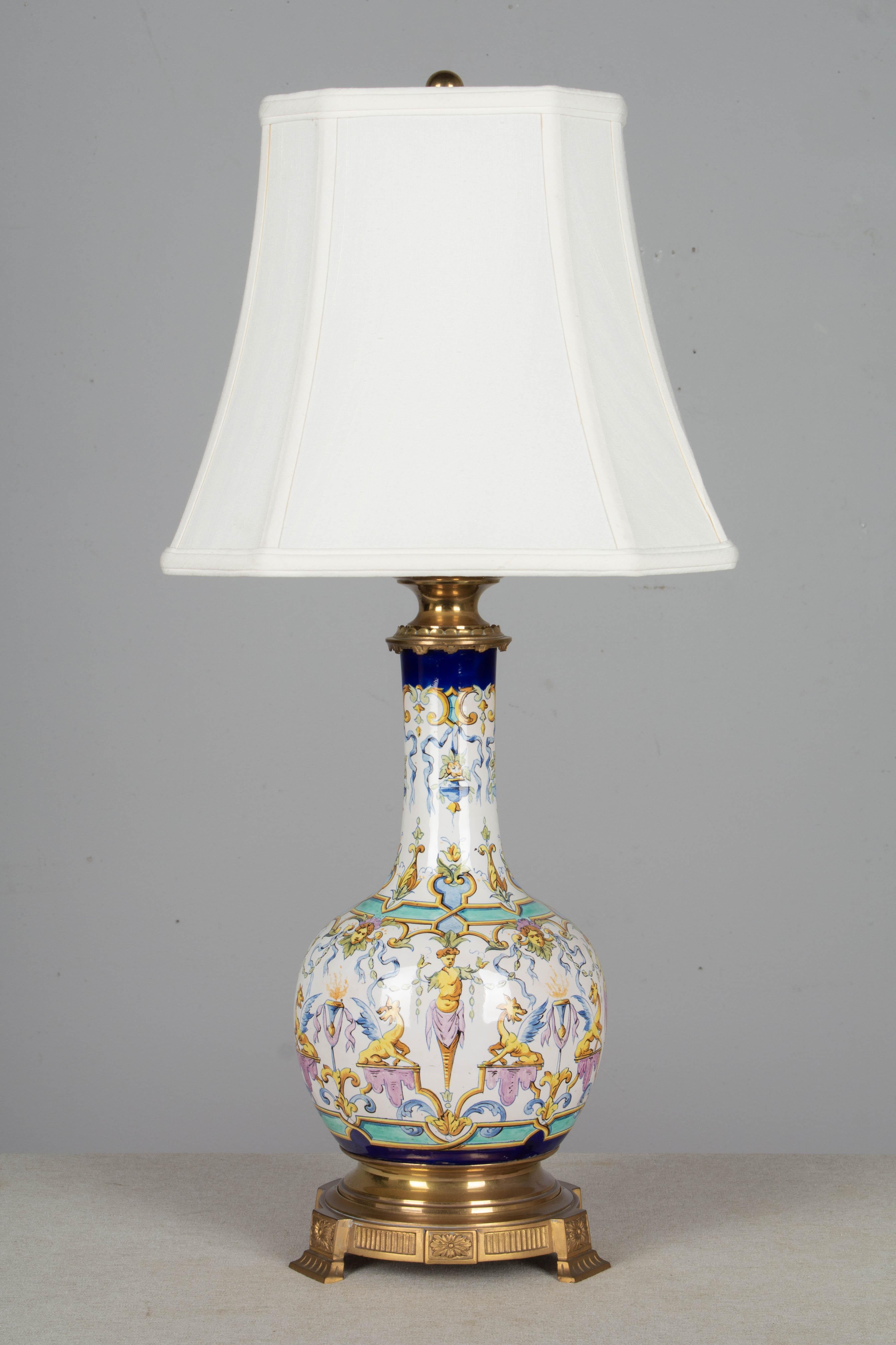 A pair of 19th century French Gien bronze mounted faience table lamps. Original bronze hardware with heavy cast base and neck, converted from oil lamps. Hand painted faience in gold, lavender, turquoise and cobalt blue on white ground. The