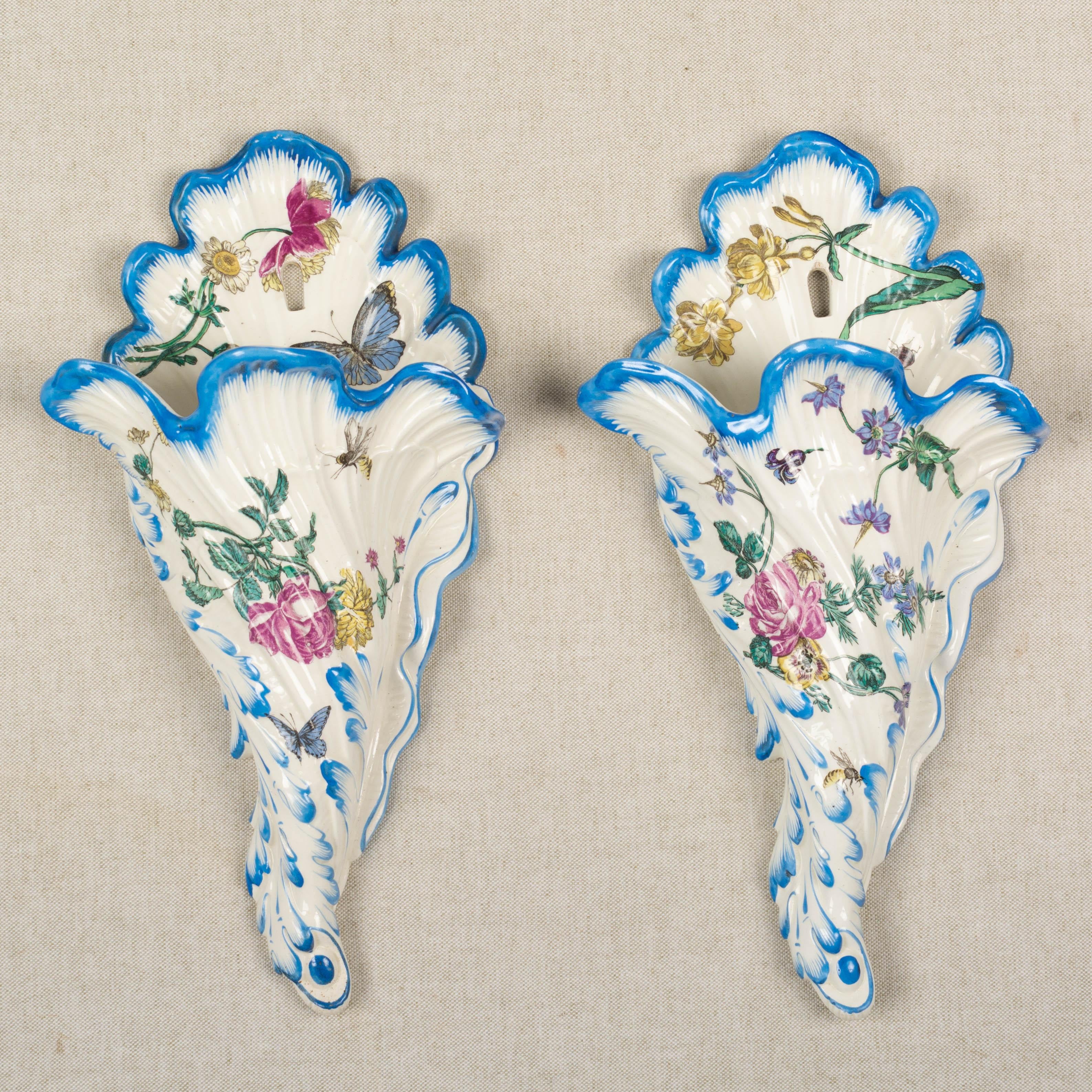 A pair of 19th century French Gien faience urns with hand-painted floral decoration. Nice form with double handles and square pedestal base. Lids with strawberry knobs. Gien stamp on underside, circa 1866. Measures: 16.5