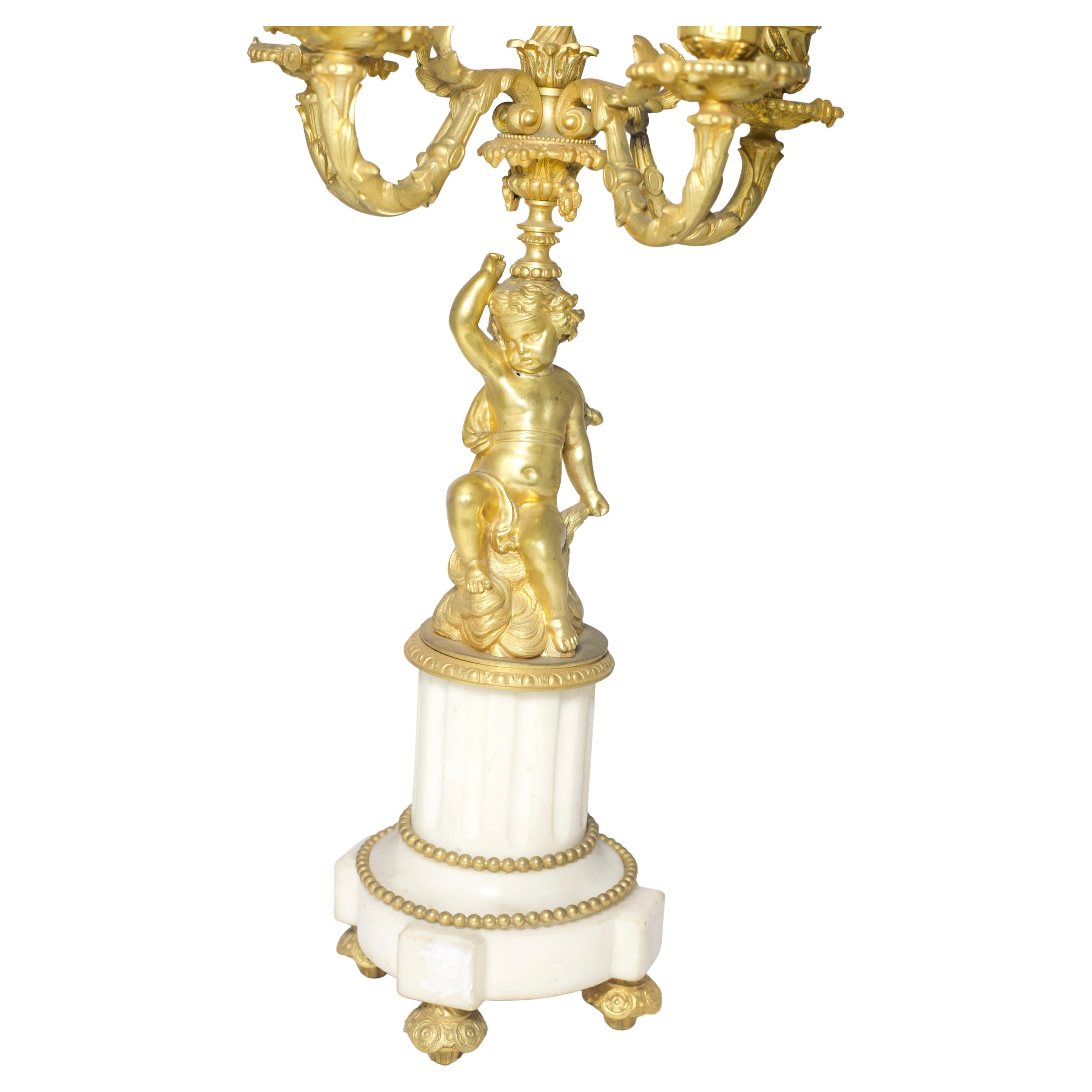 Este impresionante par de candelabros franceses del siglo XIX muestra la elegancia y opulencia de la época, con cinco brazos de vela e intrincadas figuras de querubines de bronce dorado. Los querubines están bellamente esculpidos con finos detalles,