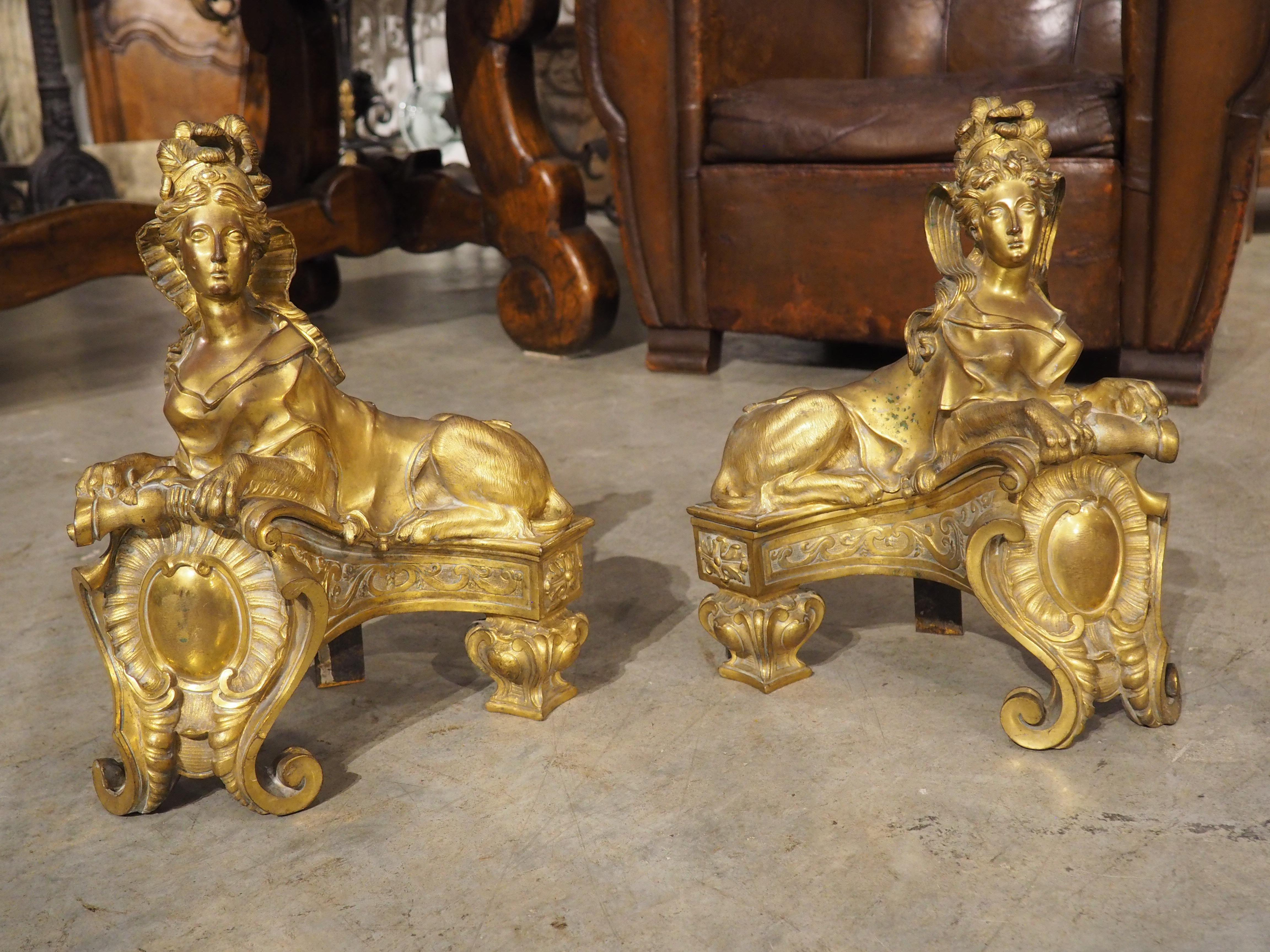 Inspired by an 18th century limestone sculpture that guards the entrance of Chateau de Chantilly in France, this pair of gilt bronze chenets are in the form of a sphinx, which is the face of a woman with the body of a lion. Our chenets would have