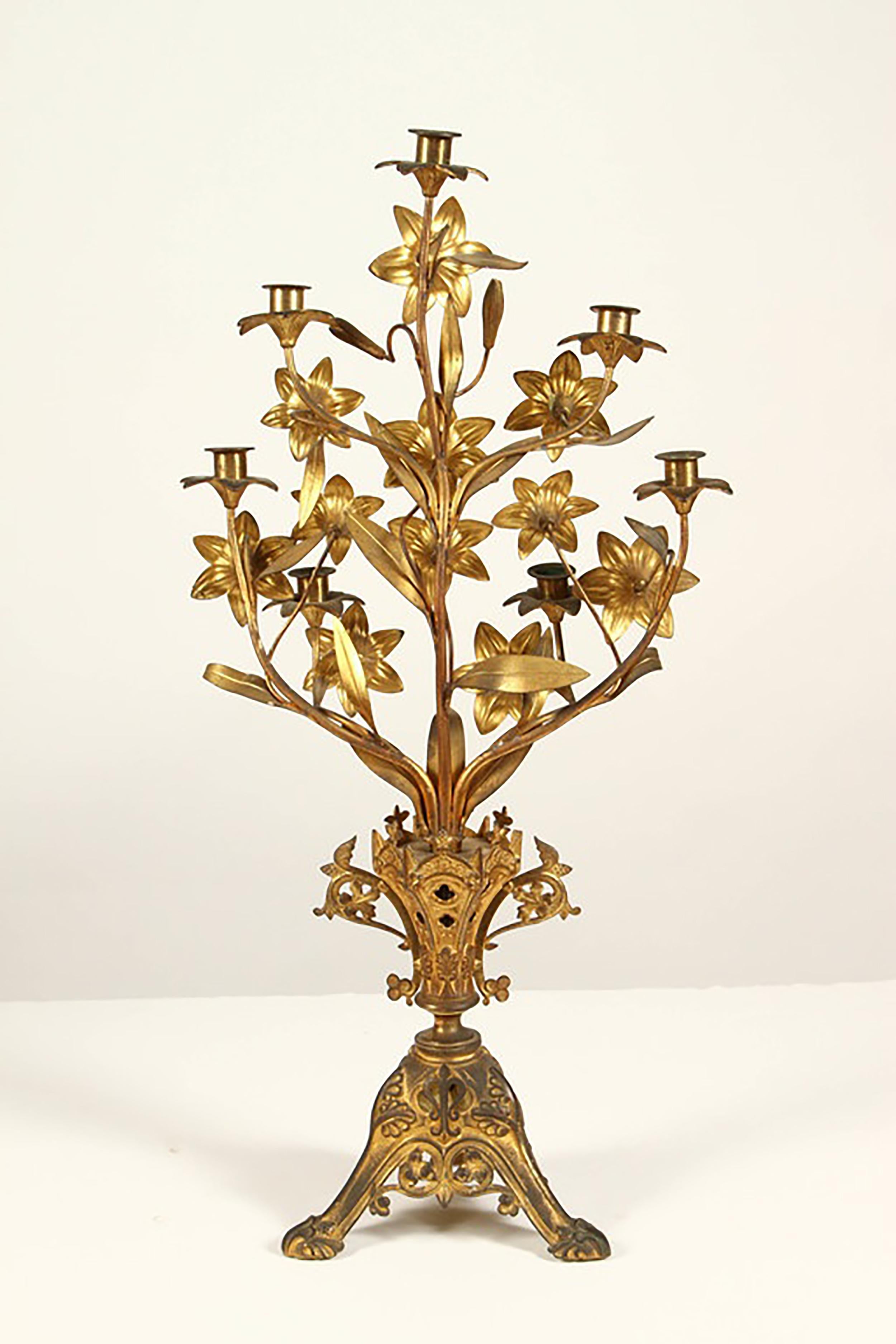 A pair of 19th century gilt-metal five-light candelabra in the style of the Baroque. Each cast as a bouquet of lilies, the stems rising from an elaborate foliate-cast vase with scrolled handles, on a tripartite base with scroll feet.