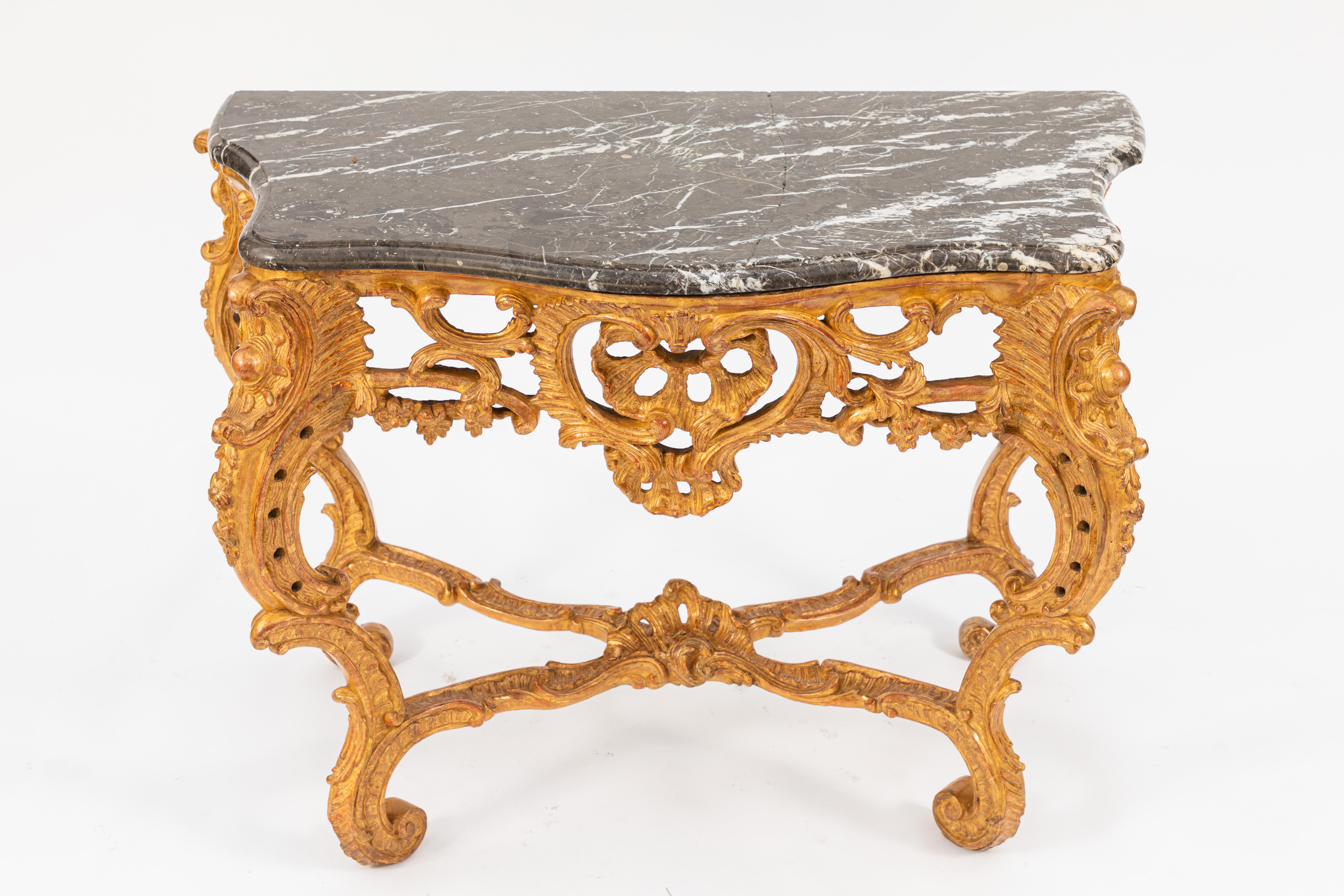 Pair of early 19th century French giltwood consoles with marble tops. The marble tops are believed to be original as the backs are hand chiseled. One marble top has a repair. These consoles were purchased at Christies.