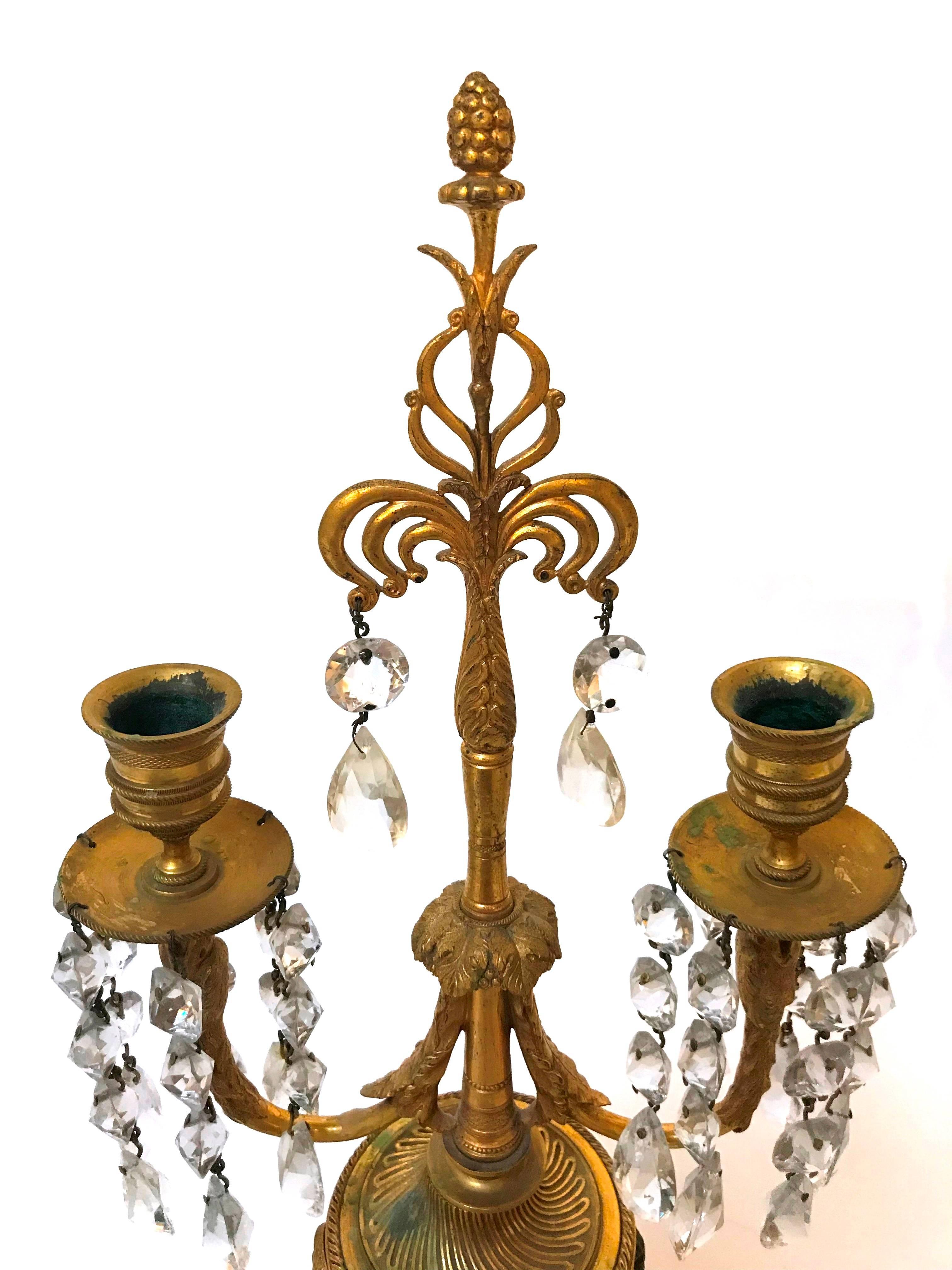 A nice pair of Napoleon III two-light candle stands made of marble cassolettes with bronze rams heads, hoof feet and candelabra with drop crystals.
