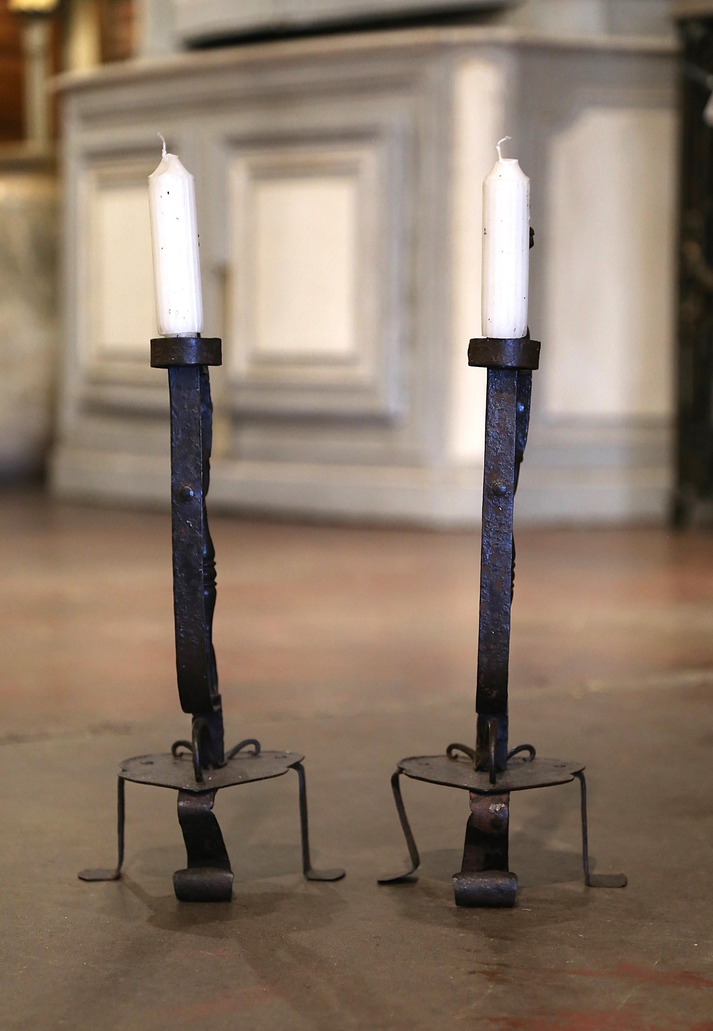 Decora un caminetto o un buffet con questa elegante coppia di candelieri antichi. Forgiato a mano nel sud della Francia intorno al 1880, ogni candelabro poggia su una base a forma di cuore su tre piedini. Il fusto centrale è decorato con motivi a