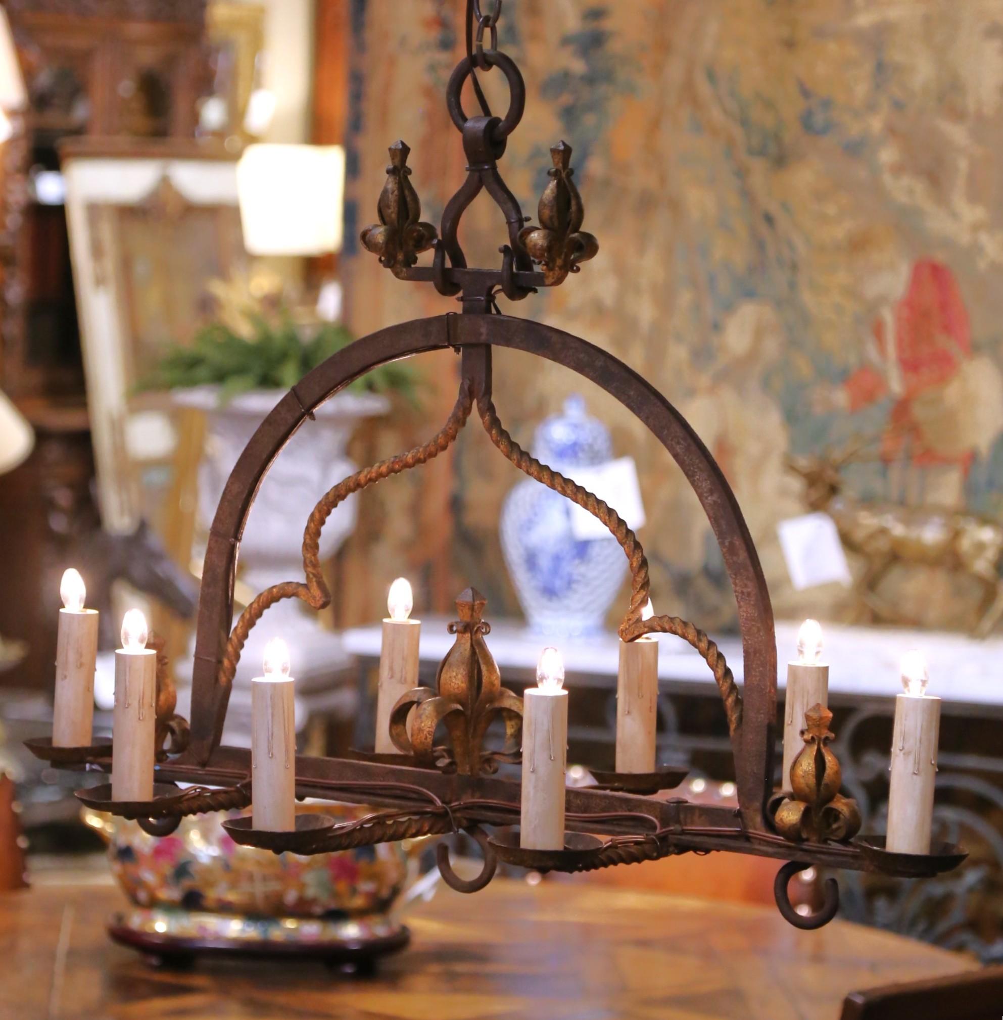 Questa impressionante coppia di lampadari antichi è stata realizzata in Francia intorno al 1880. Realizzata in ferro battuto, ogni lampada a otto luci mostra un carattere gotico con bracci elegantemente arcuati, sostegni in ferro ritorto e motivi