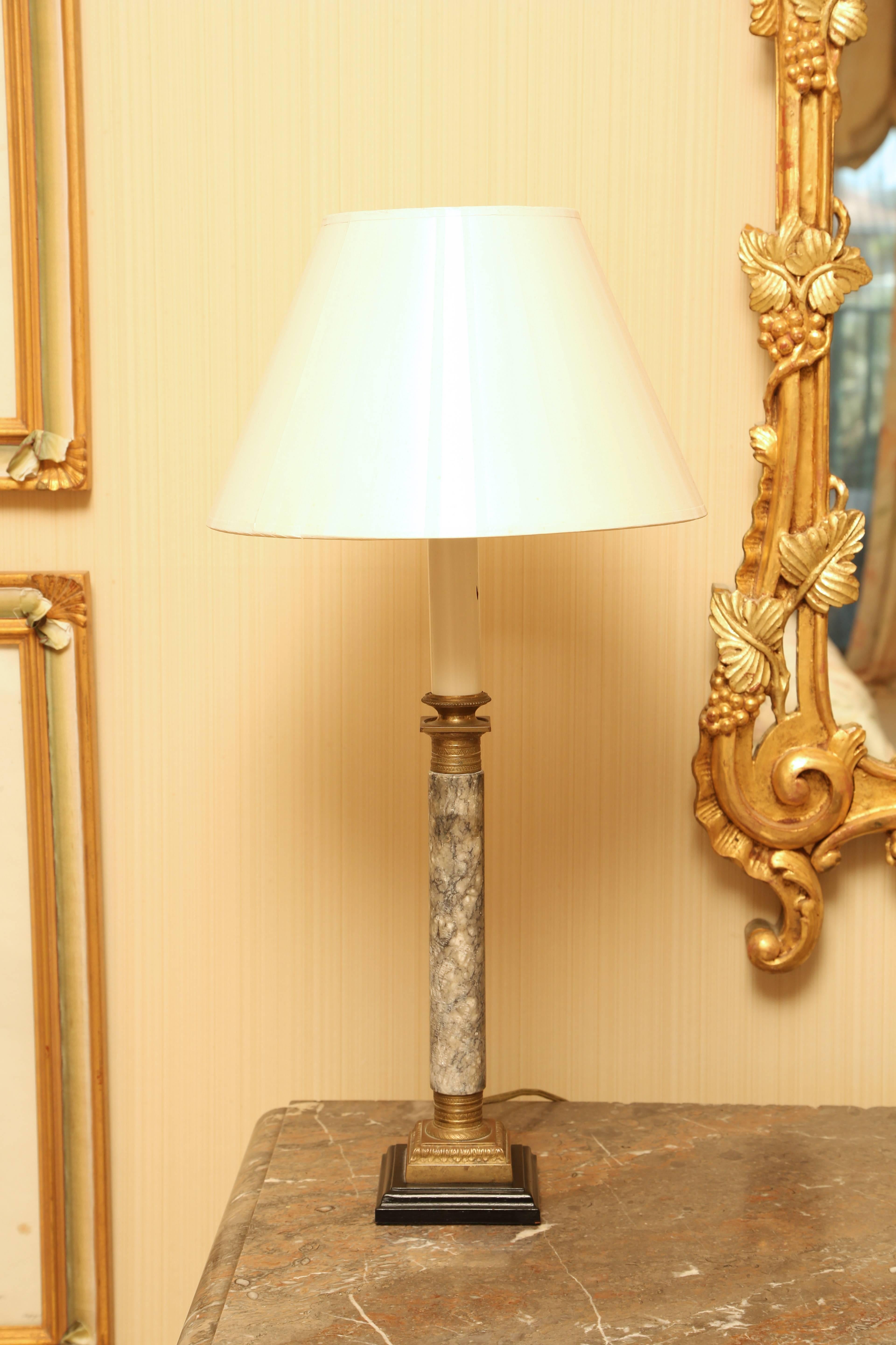 Each columnar gray marble candlestick with gilt bronze capital and base later mounted as a lamp. Each candlestick measures 12.75