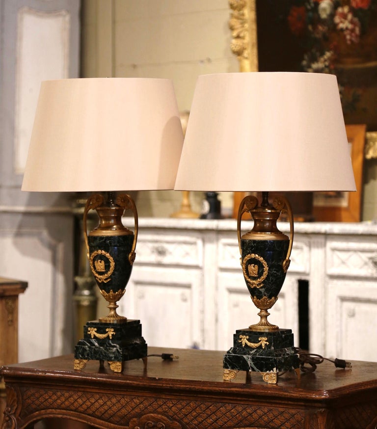 Decorate a buffet or a chest of drawers with this elegant pair of antique table lamps! Crafted in France circa 1860 and made of green marble, each carved cassolette stands on small bronze feet over a square stacked marble base decorated with swag