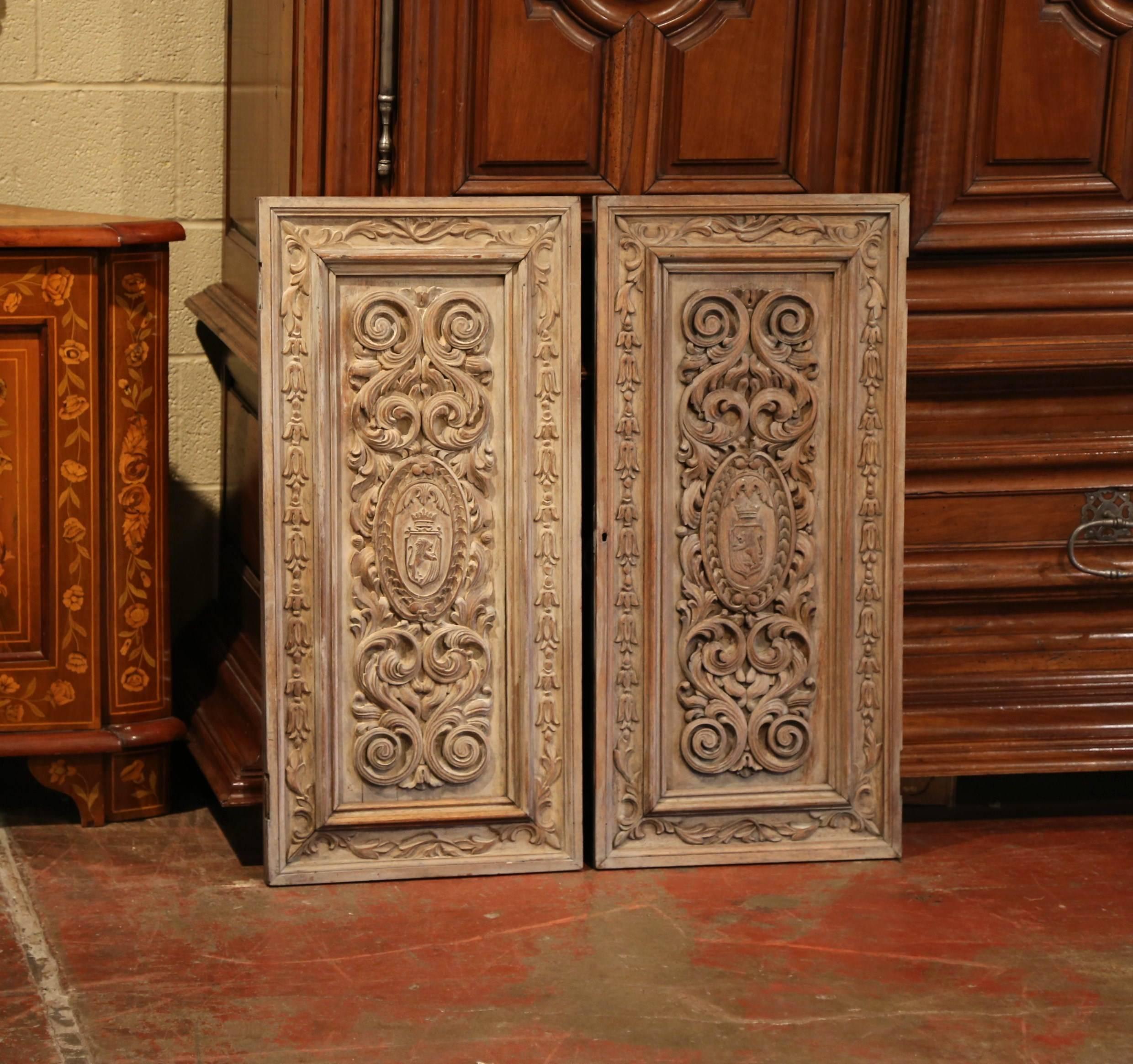 This exceptional pair of antique doors were crafted in France, circa 1880. The fruitwood wall panels feature delicate hand-carved motifs with scrolls and leaves. The central medallions show two different coat of arms. The wood panels are in
