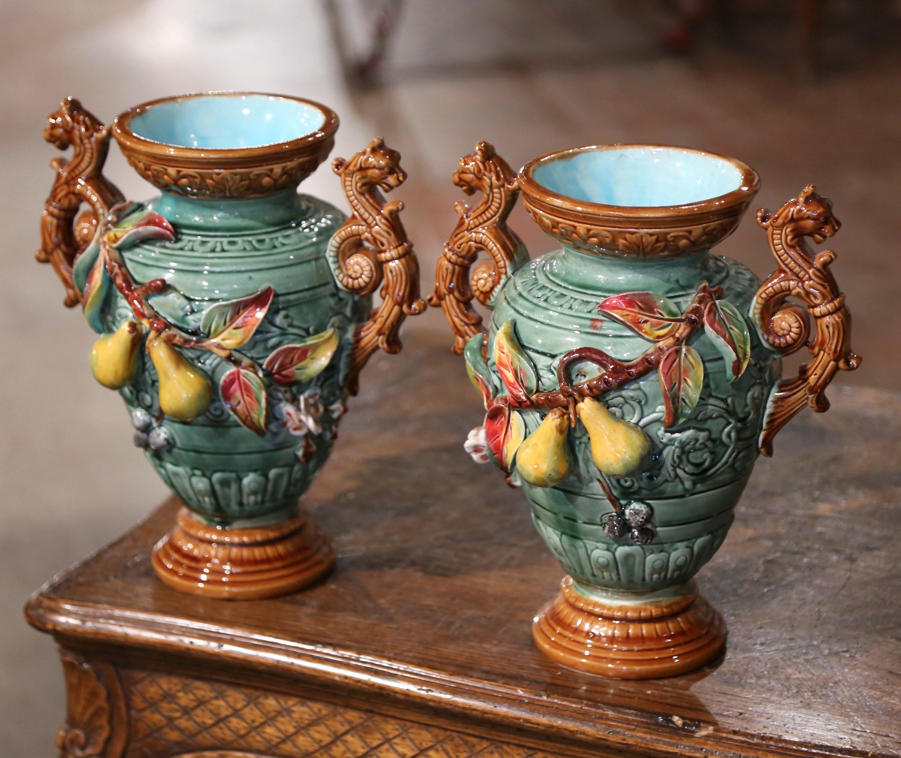 Bring colors to your mantel with this pair of antique Majolica vases with fruit motifs. Crafted in Southern France, circa 1880, this ceramic composition is a Classic example of barbotine artistry. The sculptural and colorful vessels are decorated