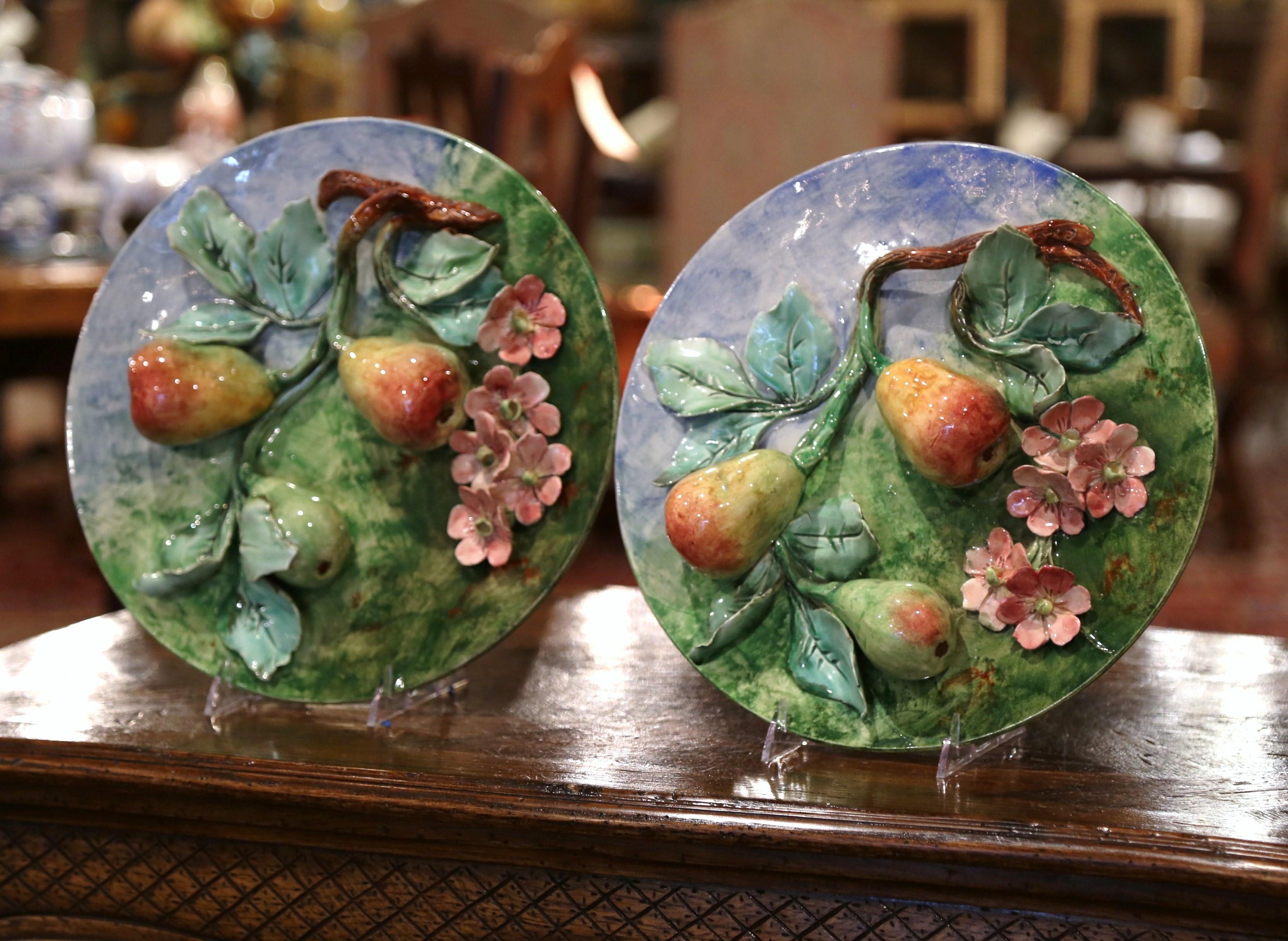 Add some color to your kitchen or dining room with this beautiful pair of antique Majolica plates, crafted in France, circa 1880, each colorful plate is decorated with a high-relief, sculptural pear fruit motifs hanging from tree branches covered