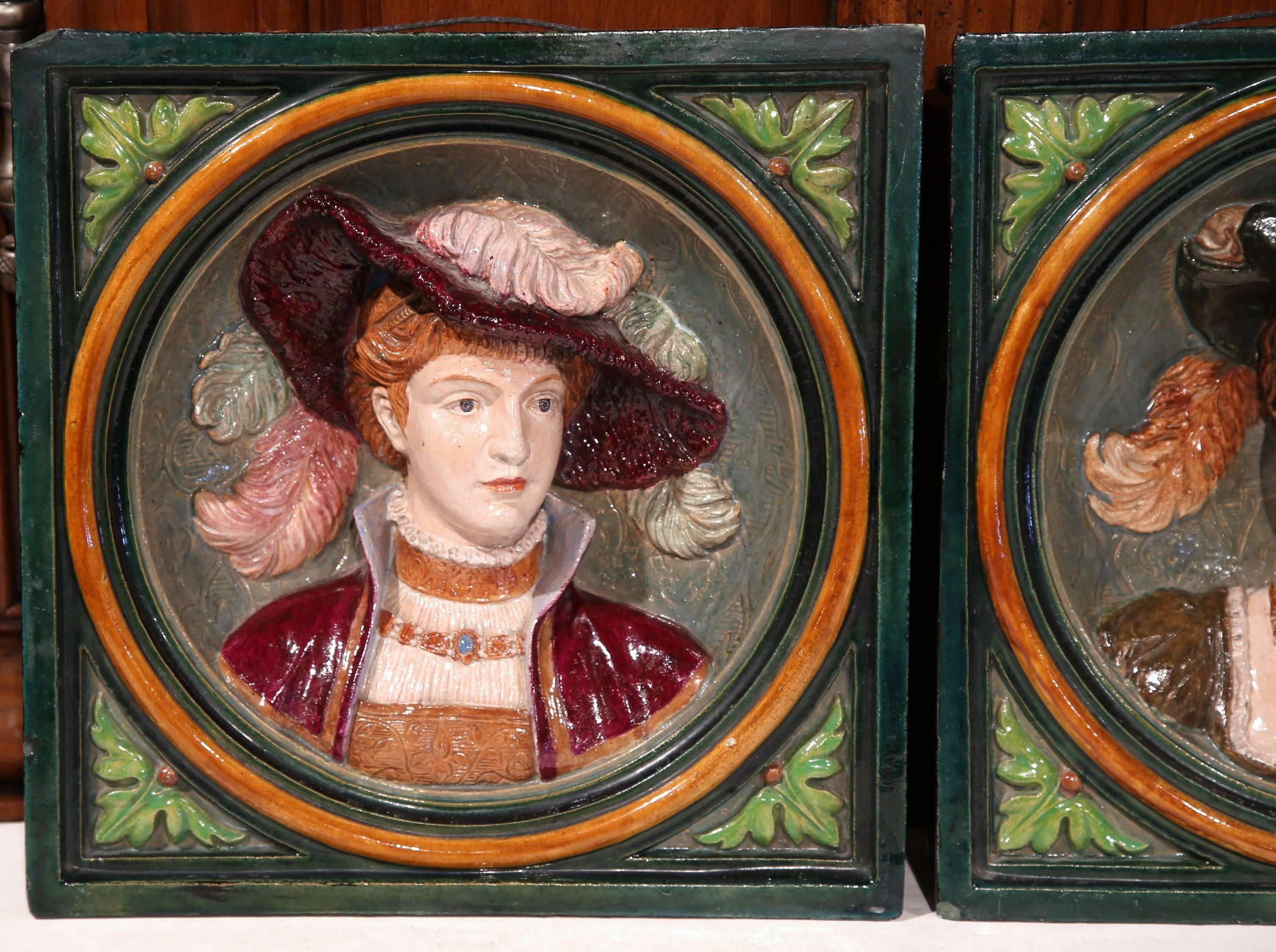 Embellish a wall or shelf with this elegant pair of antique, hand painted Majolica wall hanging plaques. Crafted in France, circa 1880, the ceramic tiles depict a man and a woman dressed in traditional Renaissance clothing. Both portrait figures are