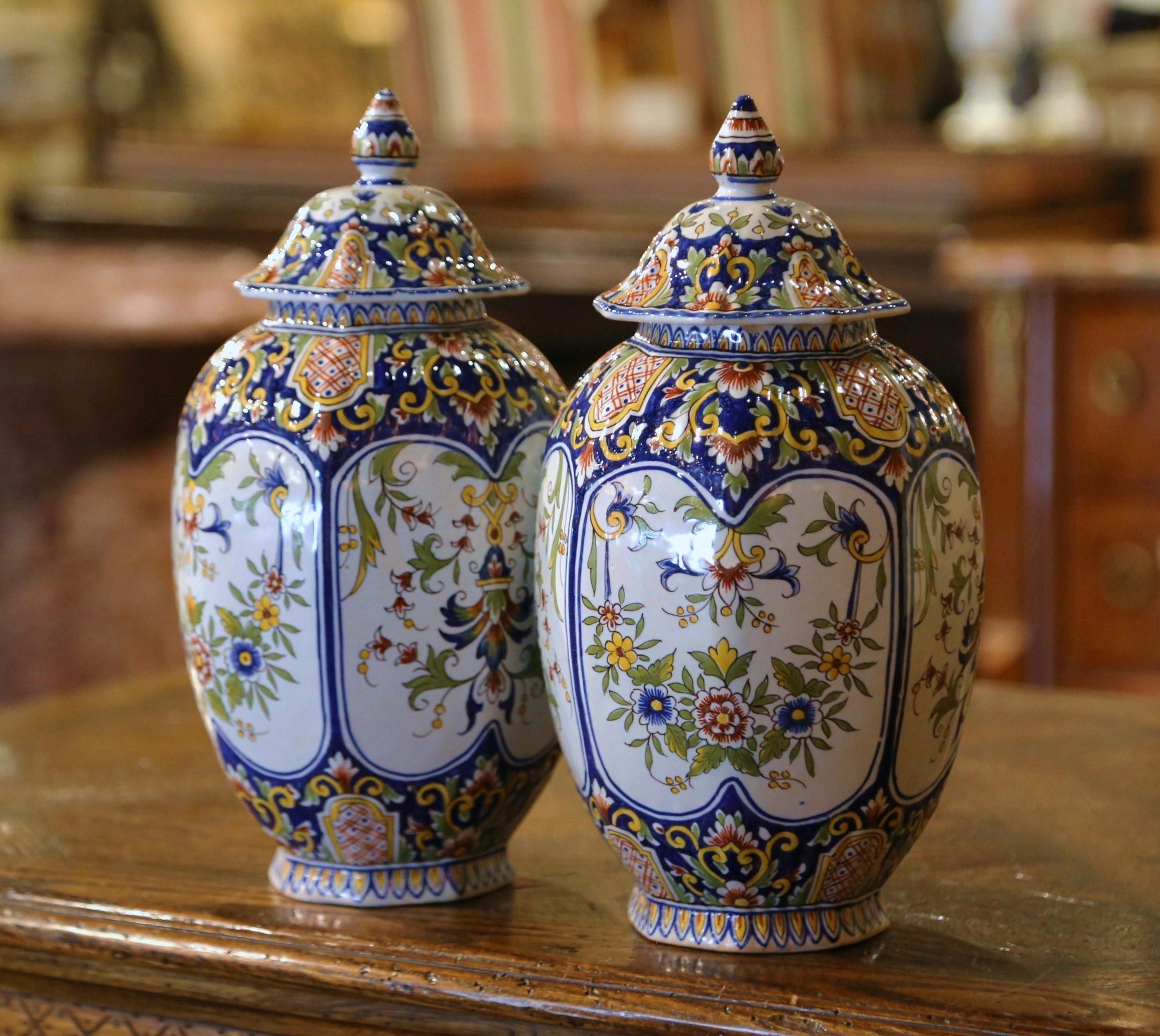 These elegant antique urns were crafted in Normandy, circa 1890. The round and colorful ceramic potiches are decorated with hand painted floral motifs in a traditional Rouen blue, white and yellow palette, including the four center medallions. The