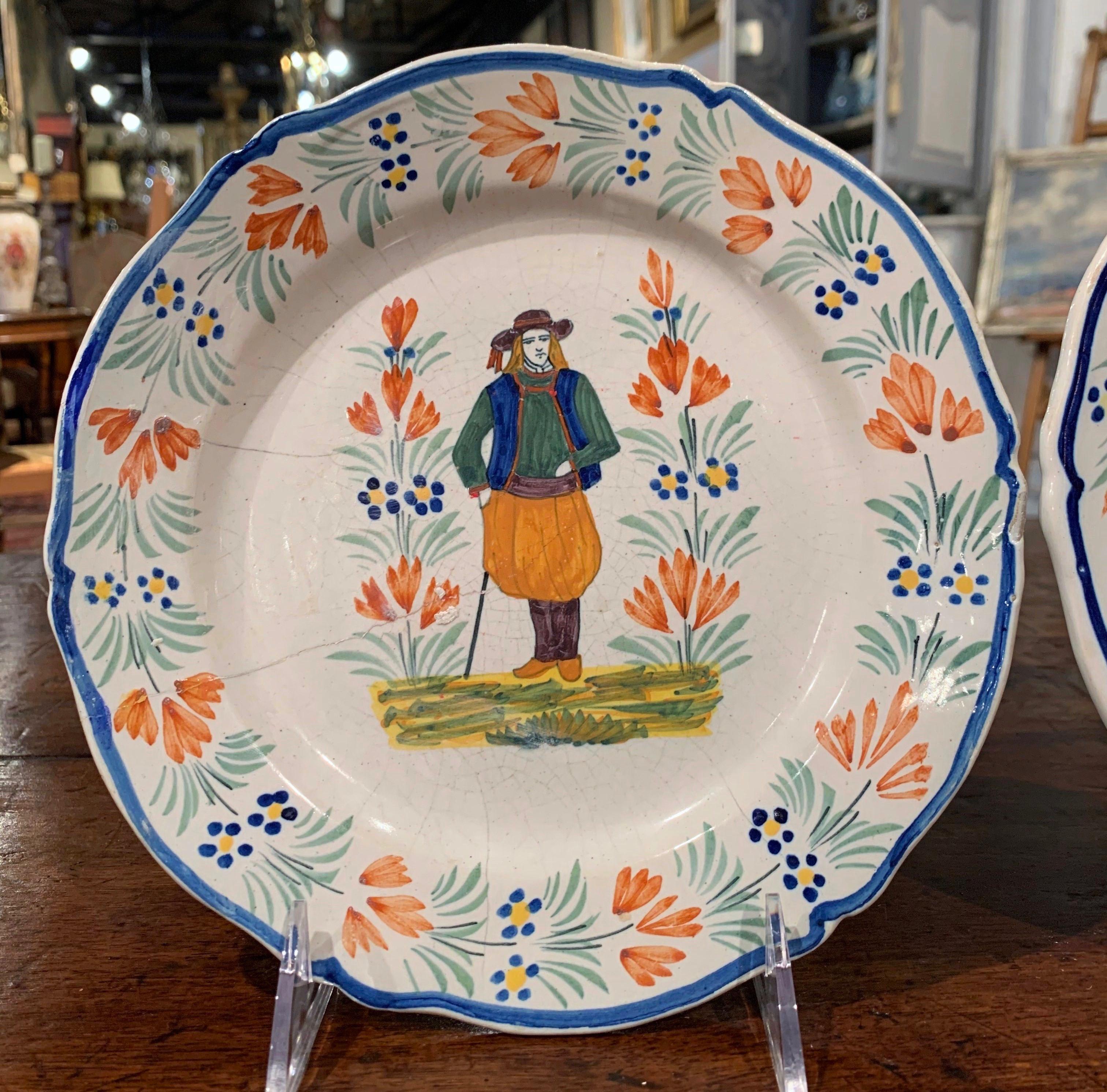 Decorate a shelf with this pair of antique decorative plates from Brittany, France. Crafted circa 1850, each faience plate is hand painted and features Breton people in traditional costumes. The plates are signed on the back Henriot Quimper France