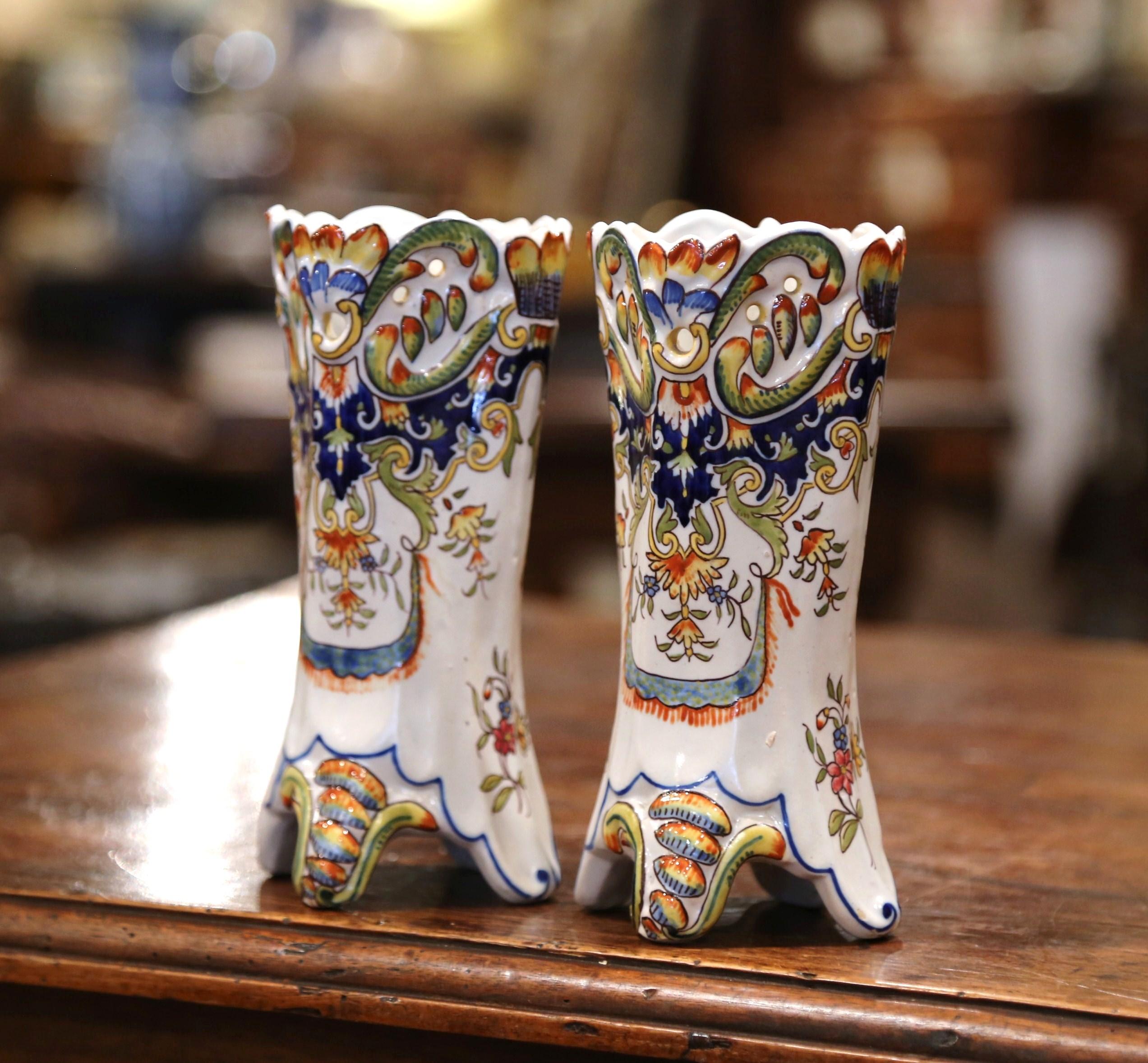 Incorporate beautiful colors into your home with this fine pair of antique ceramic vases from Rouen, France. Crafted circa 1880, the vases are ornate in decoration yet simple in shape. The small, colorful vases sit on four small feet and feature a