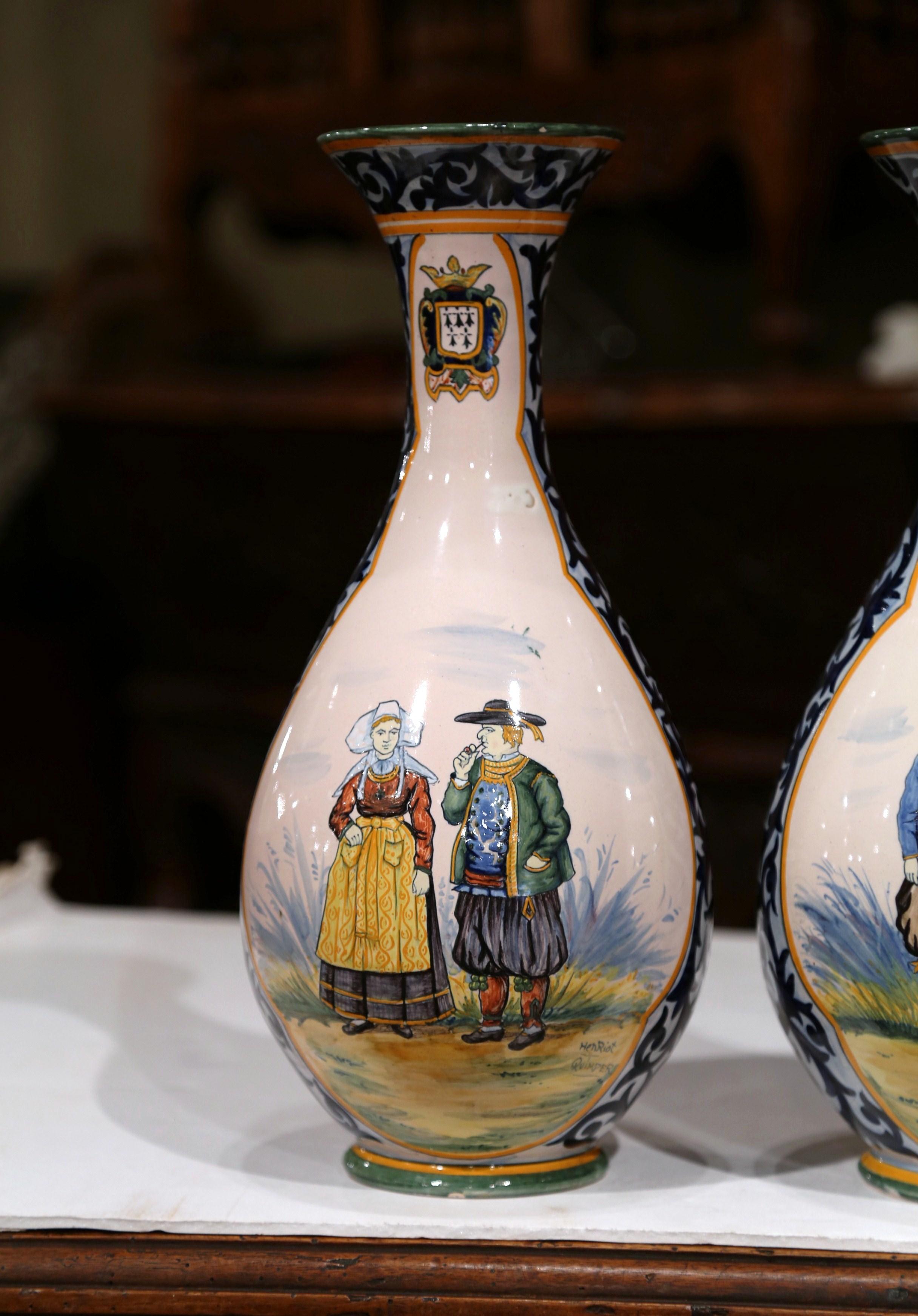 Complete your faience collection with this colorful pair of antique vases from Brittany. Crafted in Quimper, France, circa 1880, both jars are round in shape, and are hand painted with Britons people dressed in traditional outfits and embellished