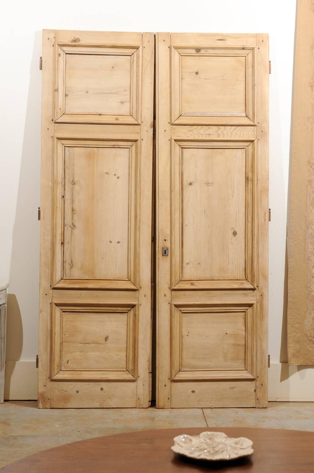 A pair of French Haussmannian wooden doors from the 19th century. This pair of French doors features the typical Haussmannian structure, made of three panels with raised molding 'à grand cadre'. The central molded panel, larger in size, is