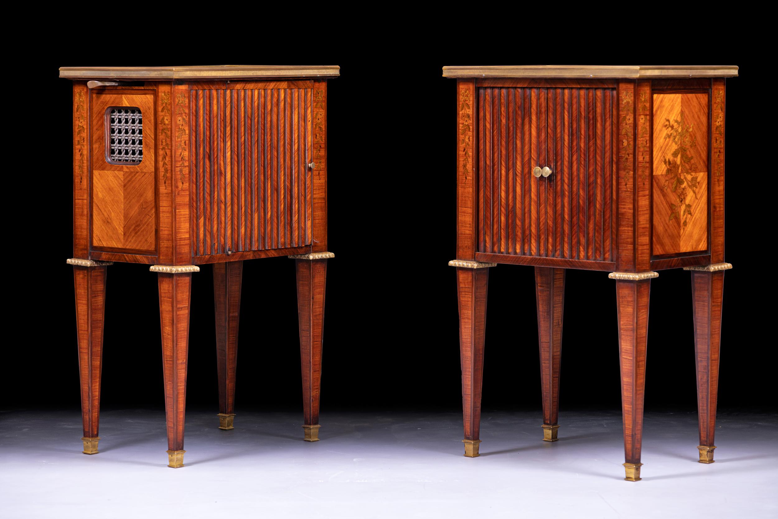 A very fine pair of 19th century French gilt bronze mounted mahogany and satinwood pier cabinets, the rectangular mahogany tops above an acanthus frieze, above a brass banded door with grill and pleated panel opening to a shelved interior, flanked
