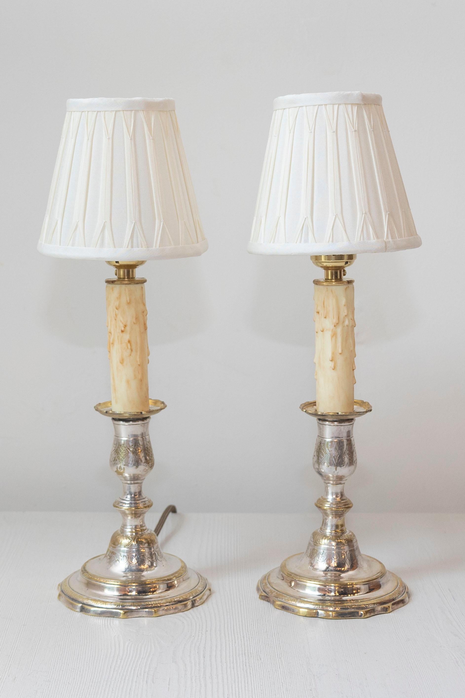 Questa raffinata coppia di candelieri del XIX secolo, realizzati in bronzo argentato e cesellato, è stata trasformata in eleganti lampade da tavolo. Le basi originali dei candelieri sono caratterizzate da dettagli intricati e da una maestria senza