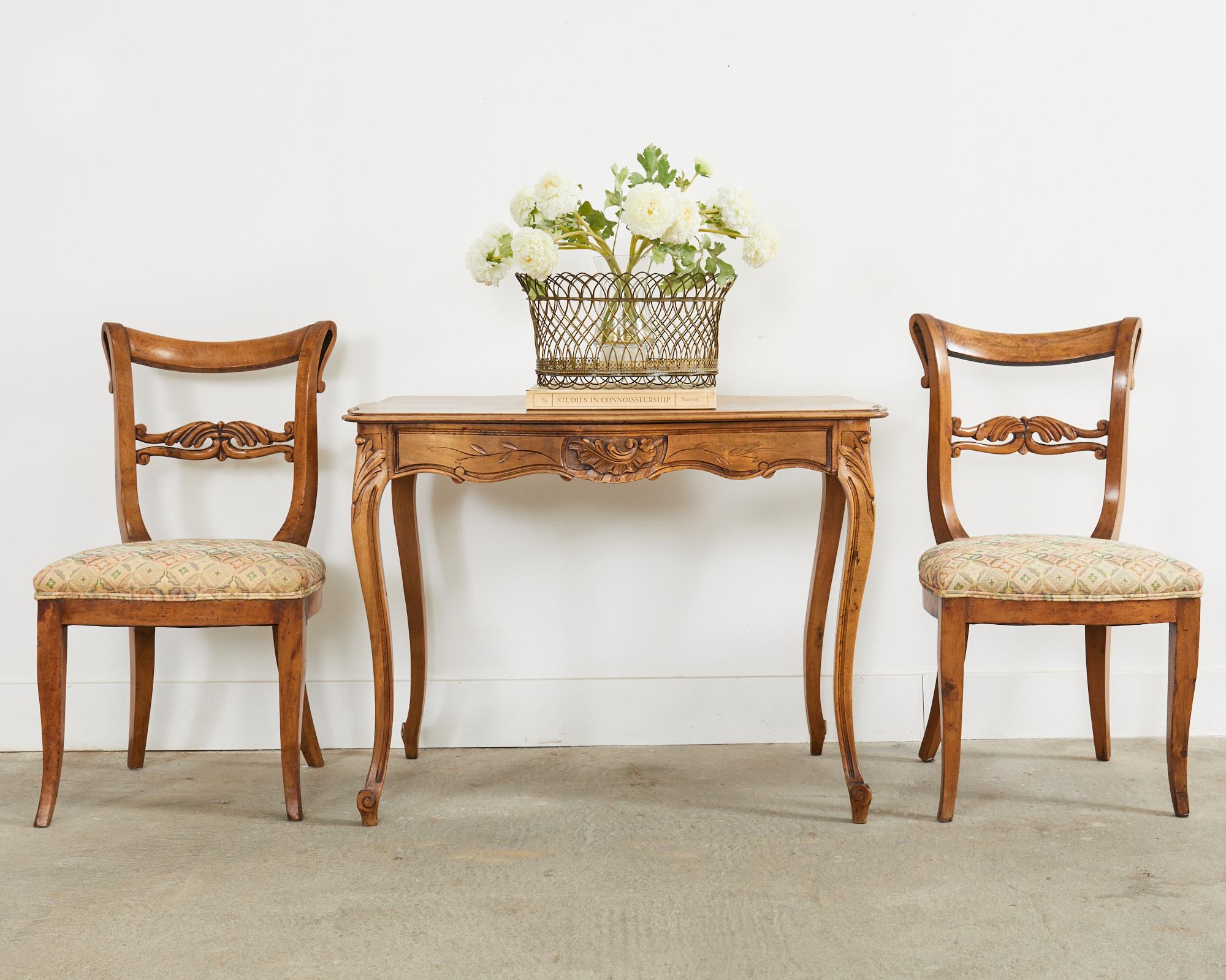 Gorgeous transitional pair of 19th century French hall chairs crafted from fruitwood. The chairs are crafted in the Louis Philippe manner and period but also still retain styling design cues from the empire period. The frames have gracefully curving