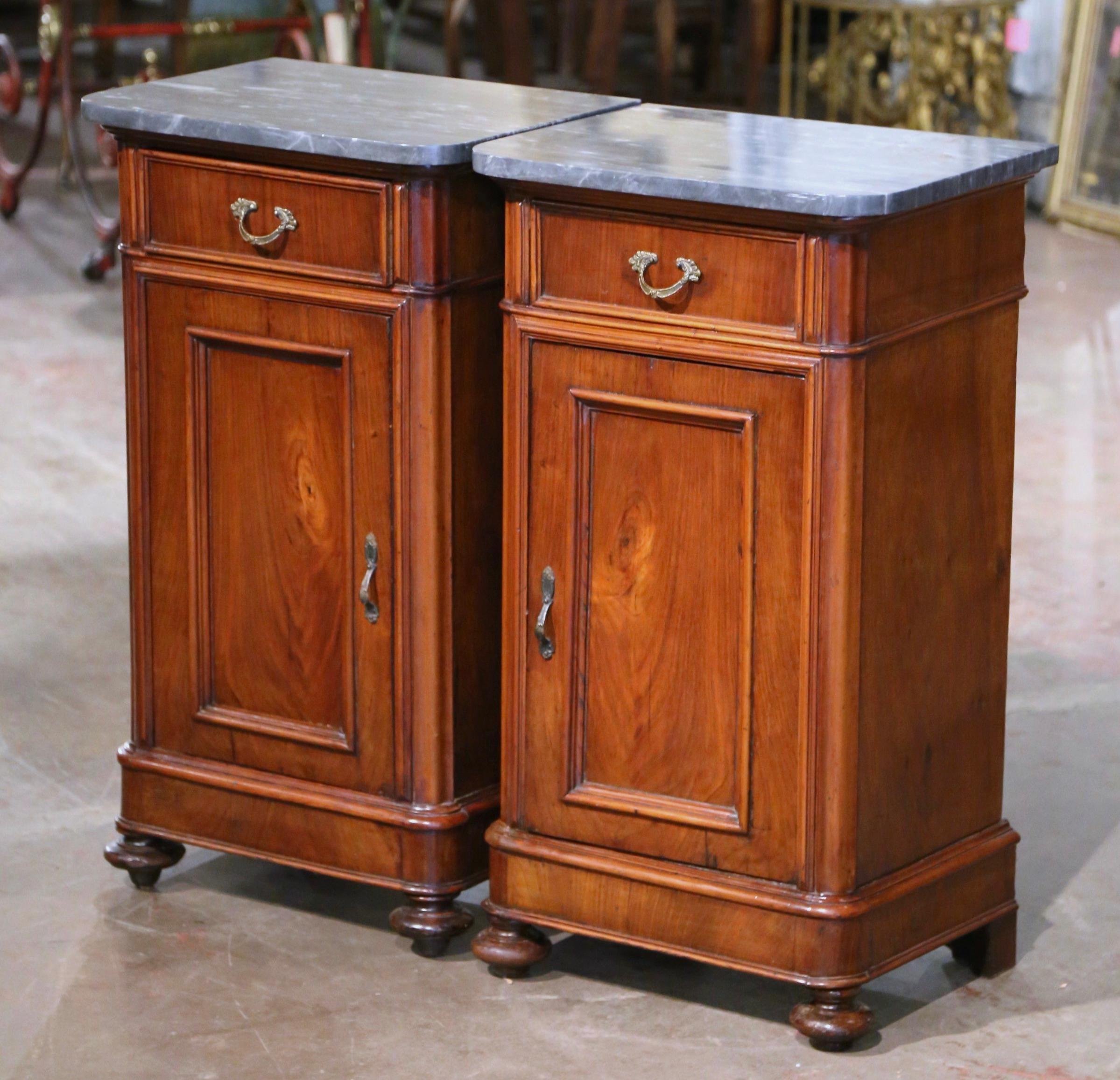 Add surface space in your bedroom with this elegant pair of antique nightstands. Crafted in France circa 1870, each cabinet built of walnut, stands on turned bun feet over a plinth base; each traditional piece with clean lines features a single
