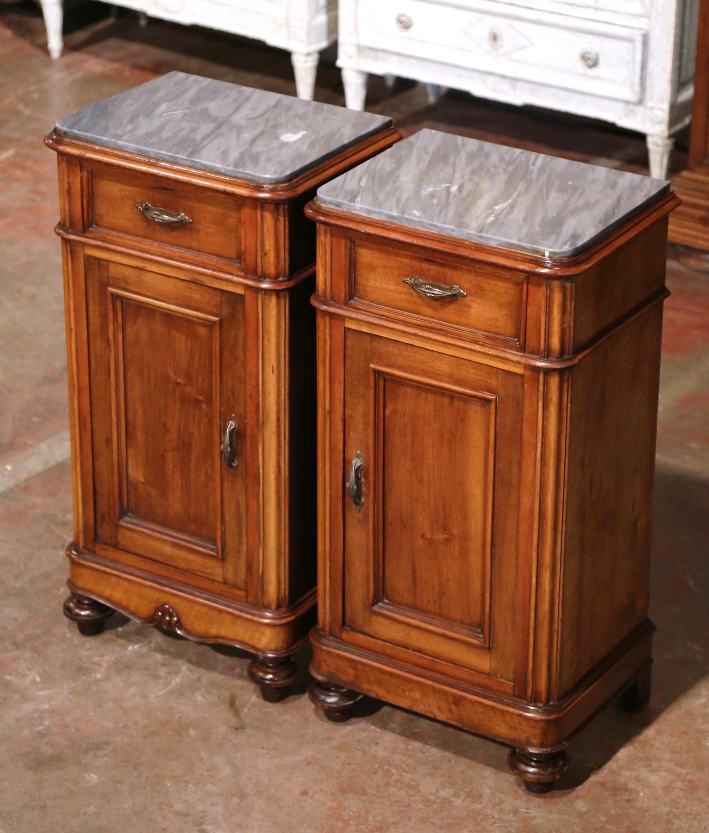 Add surface space in your bedroom with this elegant pair of antique nightstands. Crafted in France circa 1870, each fruitwood cabinet stands on turned bun feet over a plinth base (one has a foliate apron); each traditional piece with clean lines