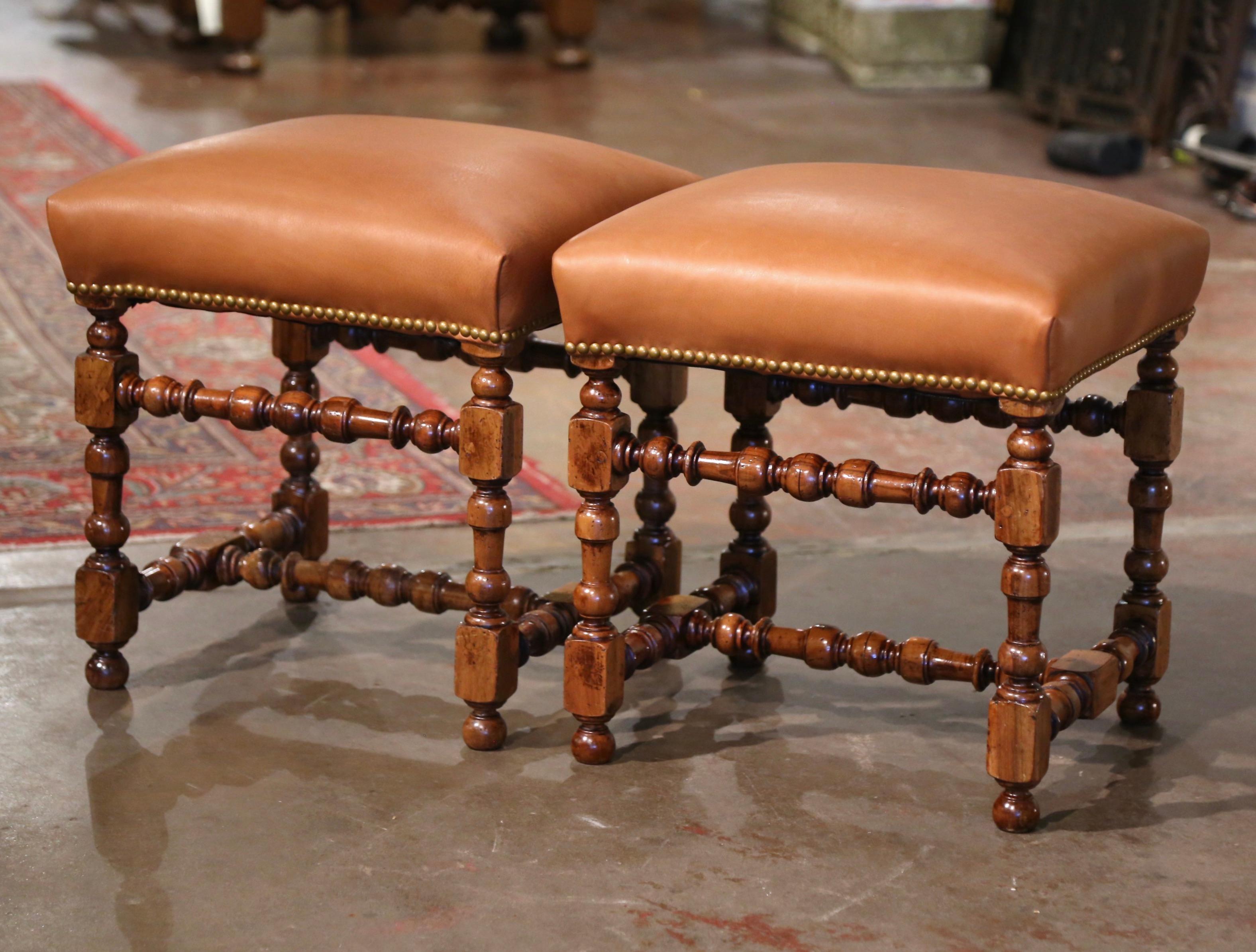 Complete a formal living room or a den with this elegant pair of antique stools. Crafted in France, circa 1880, each stool stands on carved turned legs ending with bun feet, over a bottom stretcher; each thick seating is upholstered with a tan