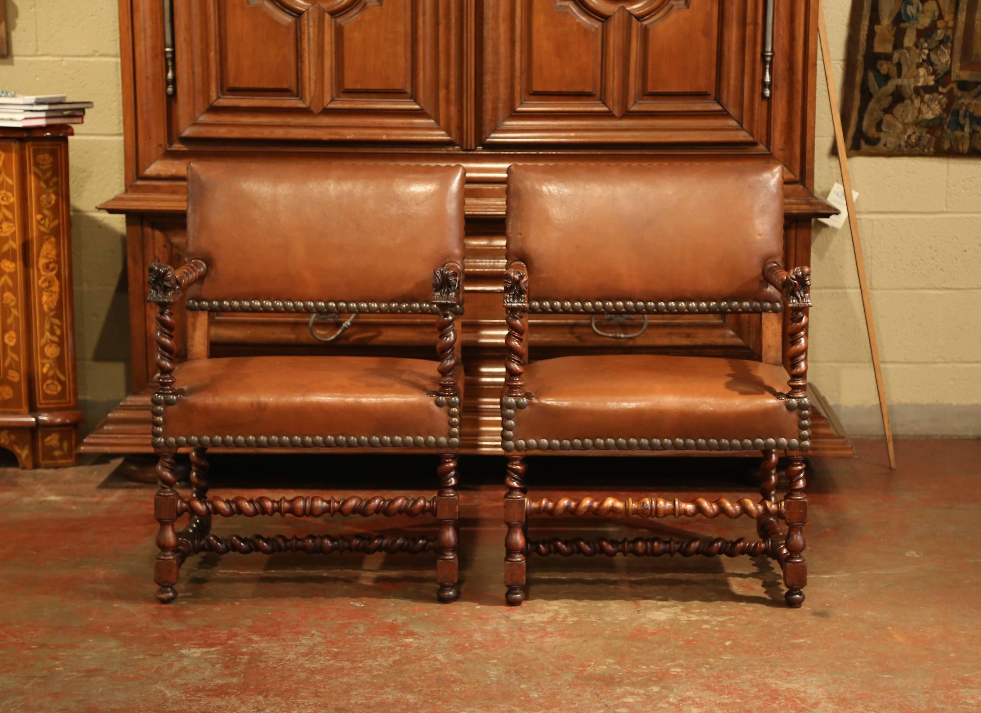 Elegant pair of antique fruitwood armchairs from the Perigord region of France; crafted, circa 1860, each chair has carved barley twist legs, stretcher and arm rests. The seat and back have the original brown leather with brass nailheads and the