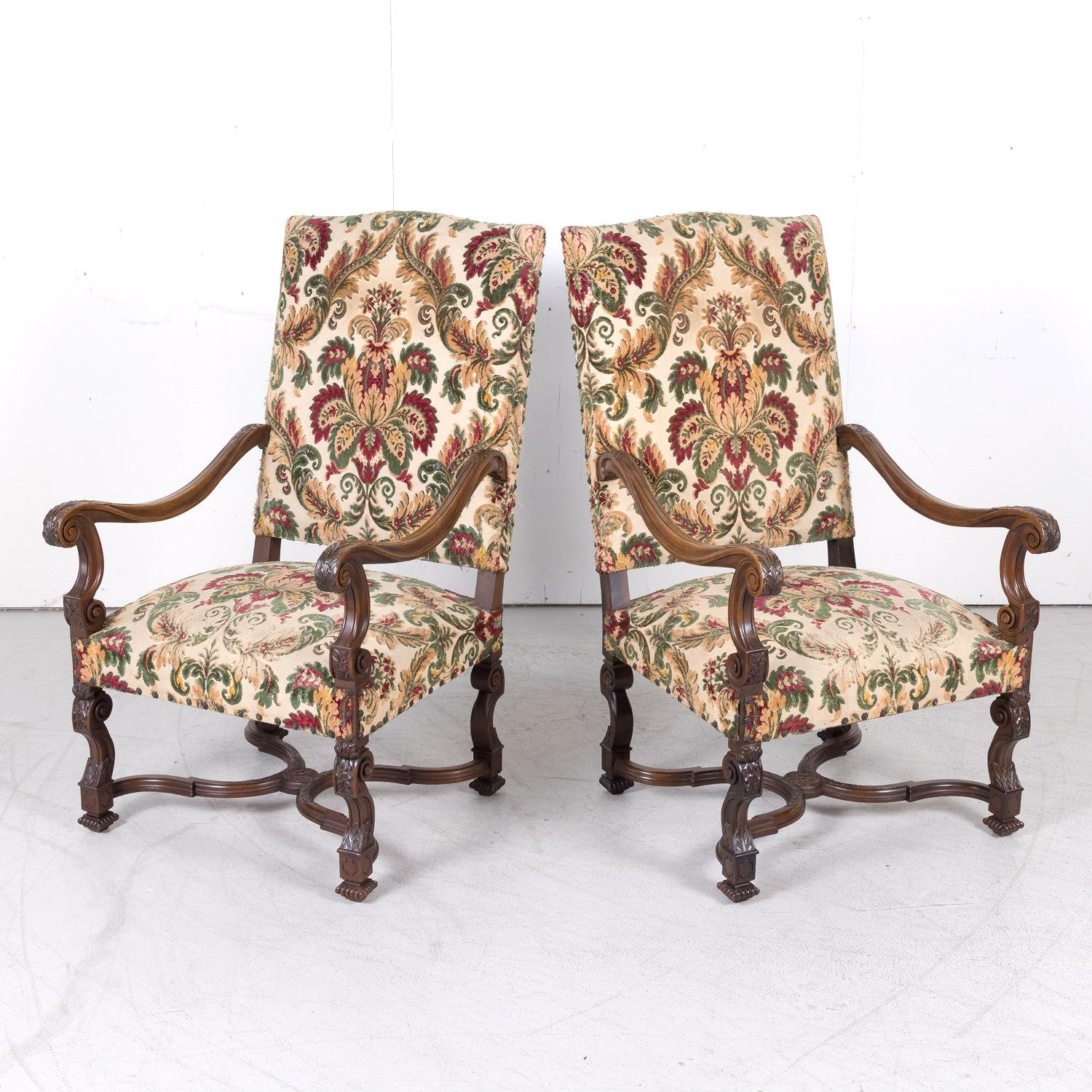 Beautifully carved pair of French Louis XIV style walnut fauteuils handcrafted in Lyon, circa 1820s, each having a high rectangle back and square section seat. Down-swept scrolling arms with volute acanthus carved armrests. Raised on a richly carved
