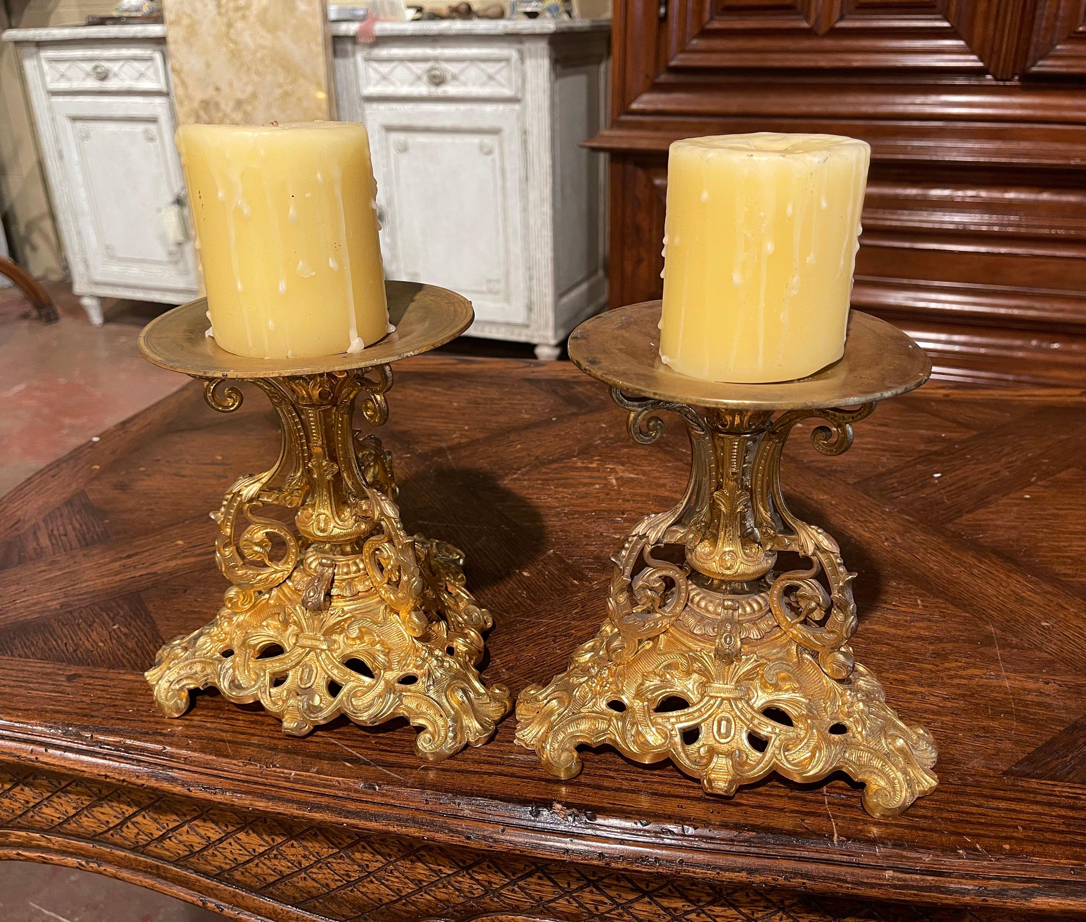 Crafted in France circa 1870, the antique candlesticks stand on a triangular base ending with scrolled feet. Each light is decorated with intricate floral and leaf motifs. The top is dressed with a round bobeche to hold a candle in place. The