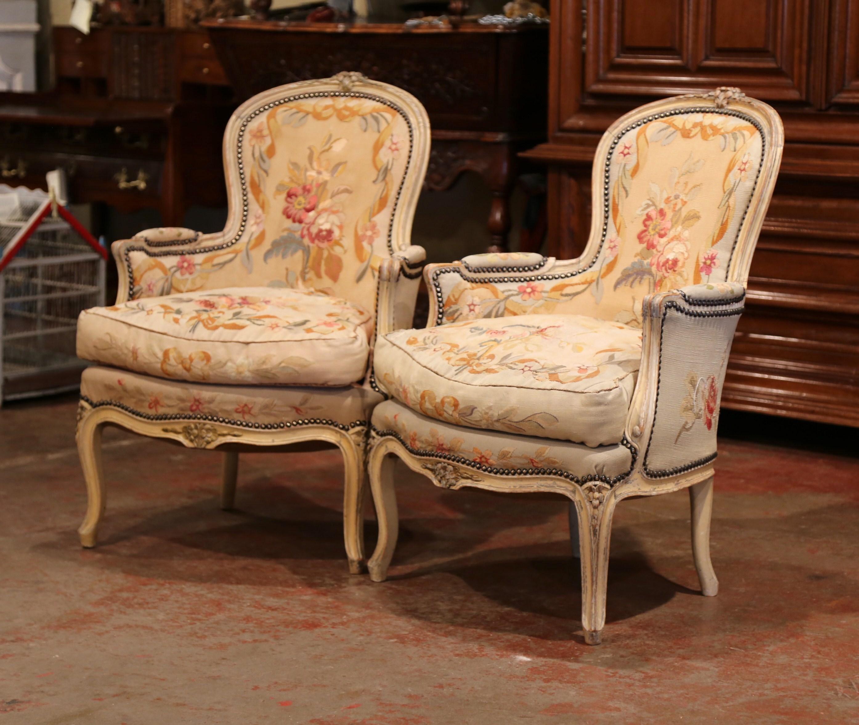 These elegant antique fruitwood bergeres were crafted in France, circa 1860. Both Louis XV style Baroque armchairs have a curved, pitched back. The chairs are decorated on the pediment, curved legs and armrests with hand carved floral