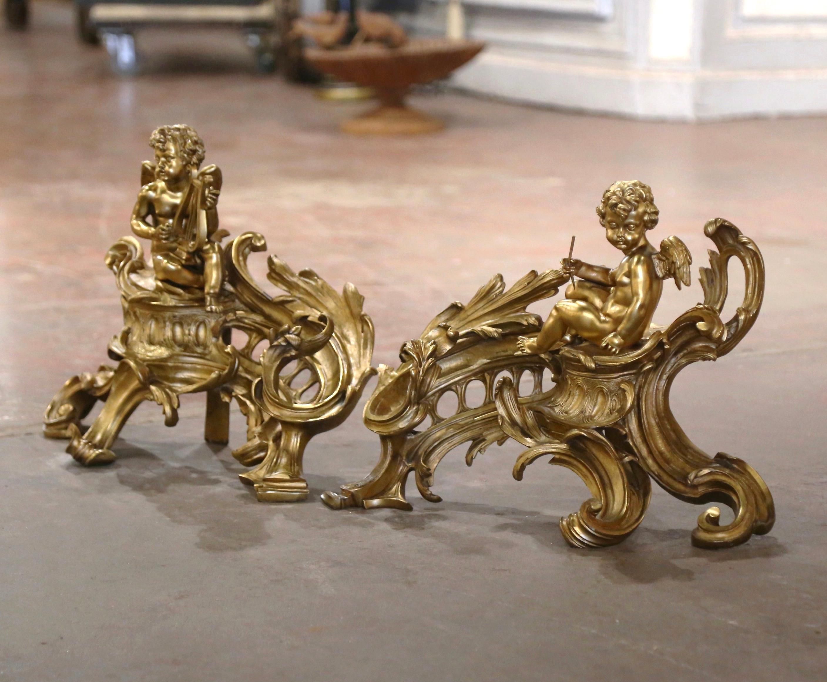 Decorate your fireplace hearth with this elegant pair of antique chenets. Crafted in France circa 1860, and built of bronze, each andiron features a cherubic figure seated atop an ornate pedestal. The cherubs are depicted in dynamic poses: one