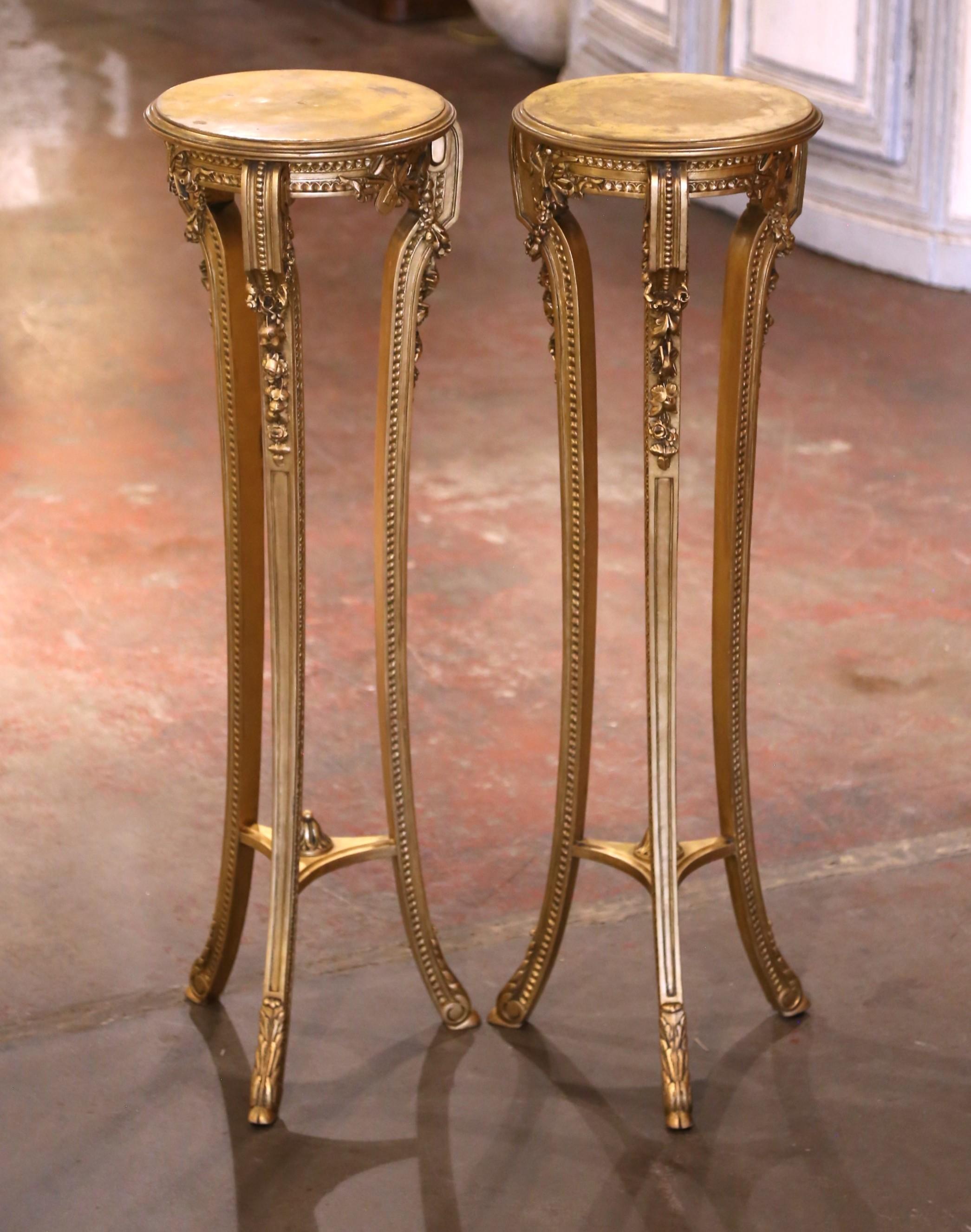 Habillez un salon ou un couloir avec cette élégante paire de piédestaux anciens en bois doré. Fabriqué en France vers 1890, chaque support présente un plateau rond soutenu par trois pieds gracieusement incurvés, reliés par un châssis en forme avec