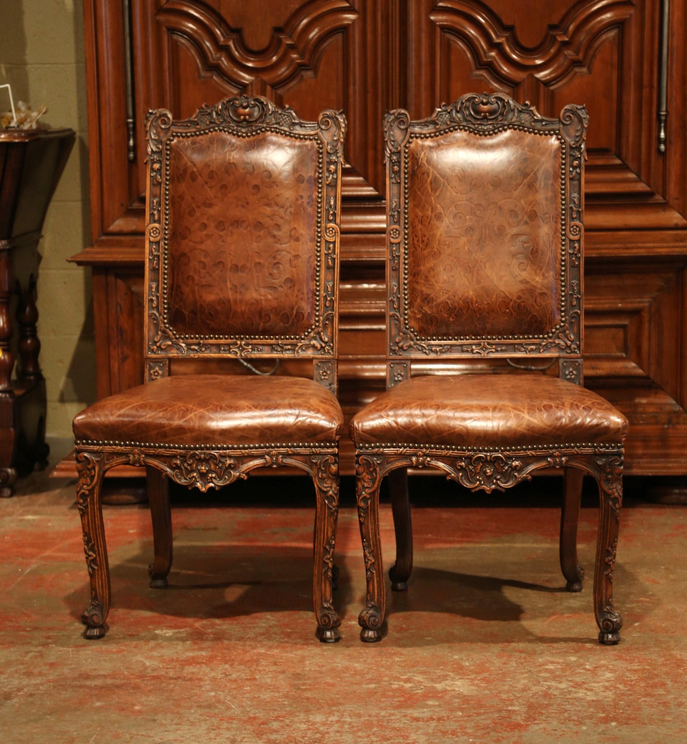 Place this elegant pair of antique side chairs in a study or library. Crafted in France circa 1860, the large fruitwood chairs stand on cabriole legs and escargot feet over a scalloped and bombe apron. The traditional chairs feature an ornate frame