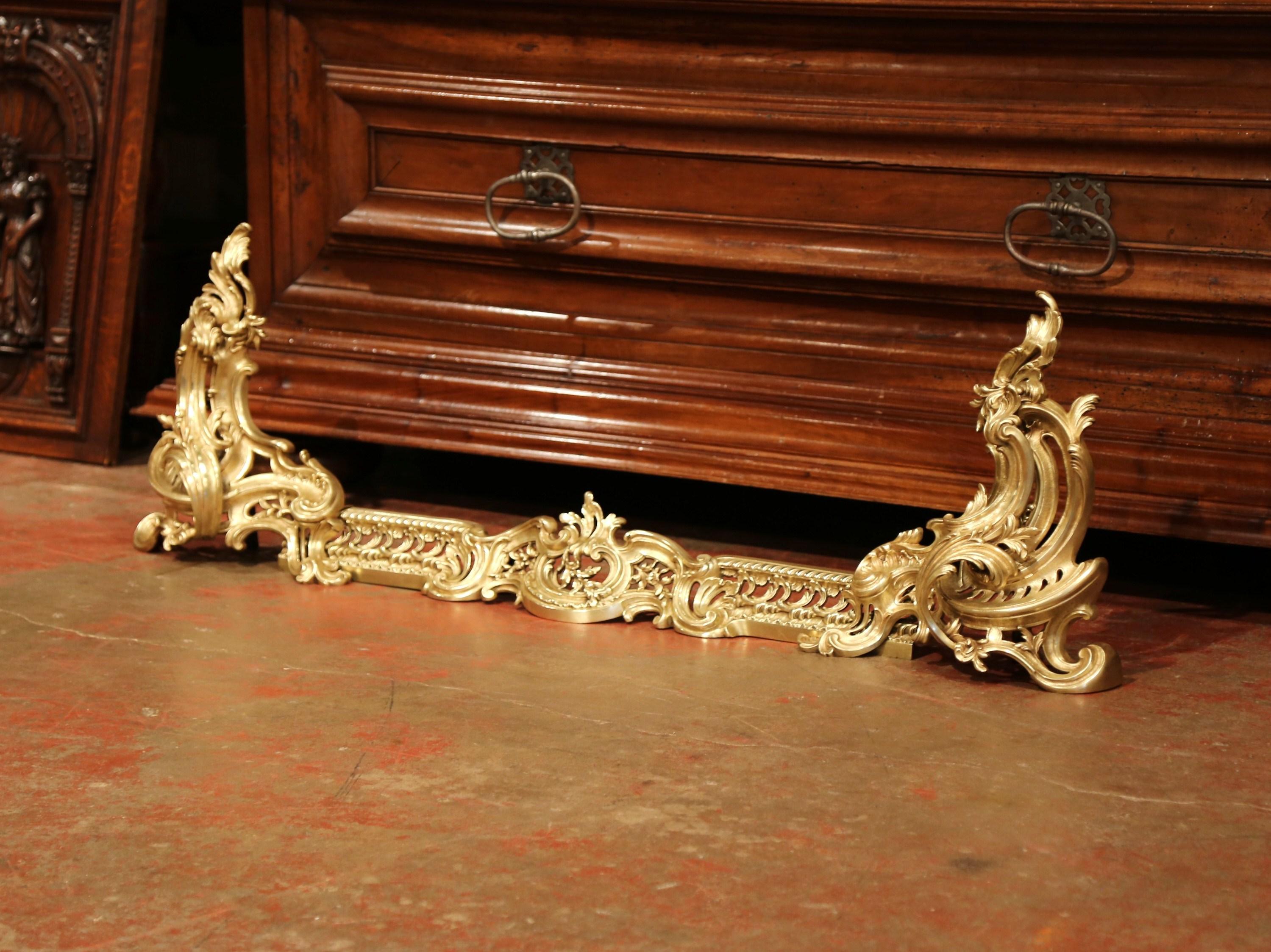 This beautiful, three-piece set would add Classic French elegance to your fireplace. Crafted in France circa 1960, the elegant rococo set includes two gilt bronze chenets and a large, matching center fender. Each piece is decorated with swirling and