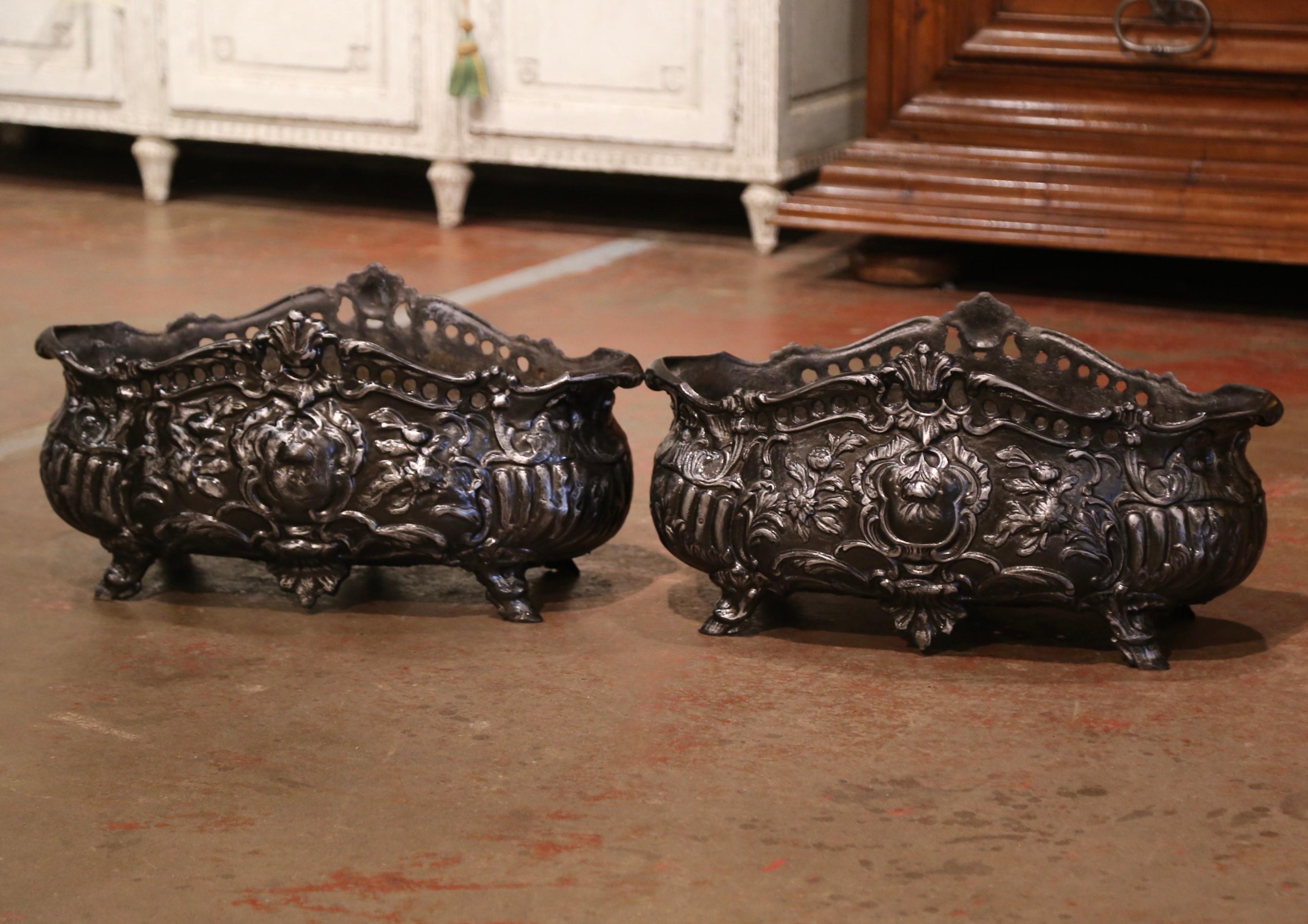 Stage your front door with this elegant pair of antique planters. Crafted in France circa 1880 and oval in shape, each jardinières stands on hoof feet over a bombe form body, and is decorated with floral and leaf motifs in high relief; the planter
