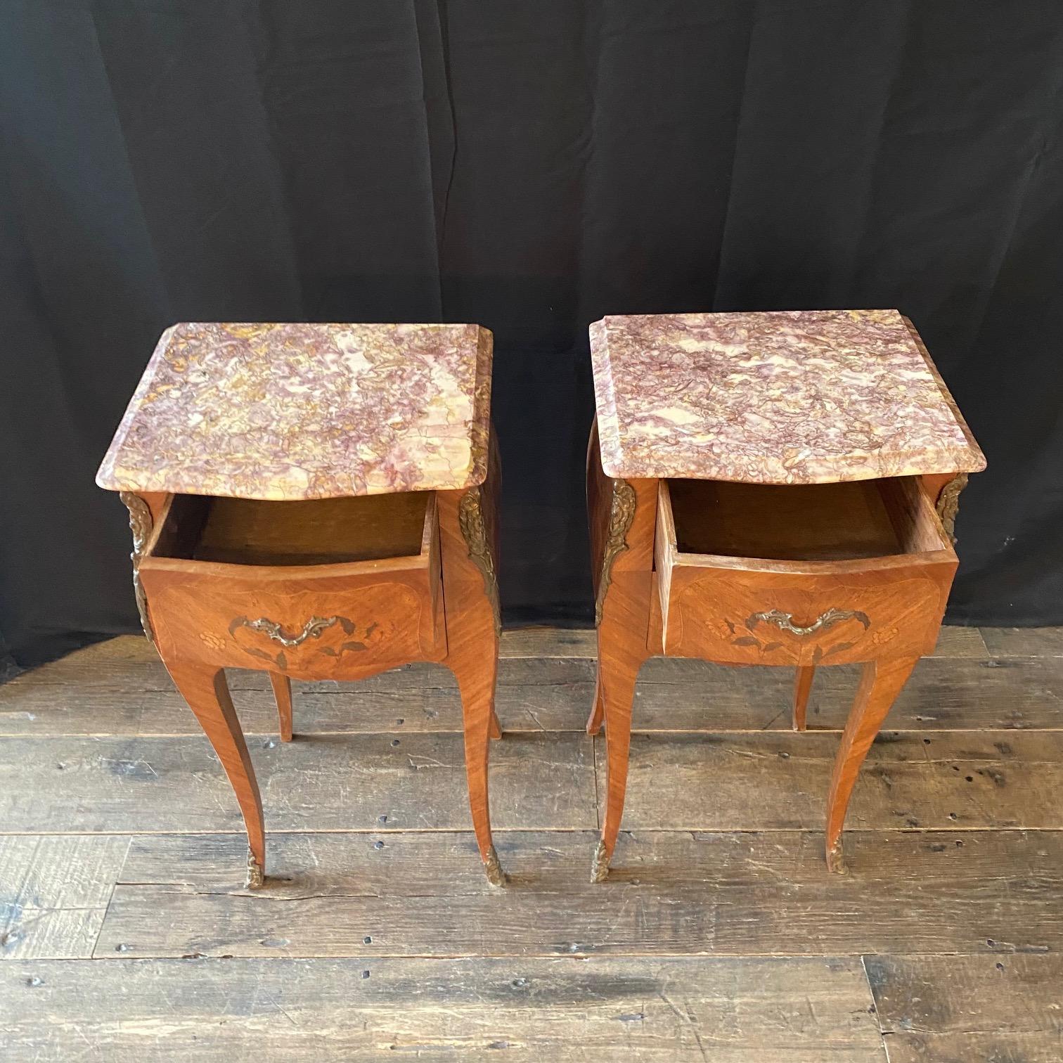 Antique Louis XV French marquetry marble night stands, side tables or bedside tables. Beautiful walnut and fruitwood, having serpentine marble tops above two inlaid and dovetailed floral drawers fitted with original brass handles and flanked by