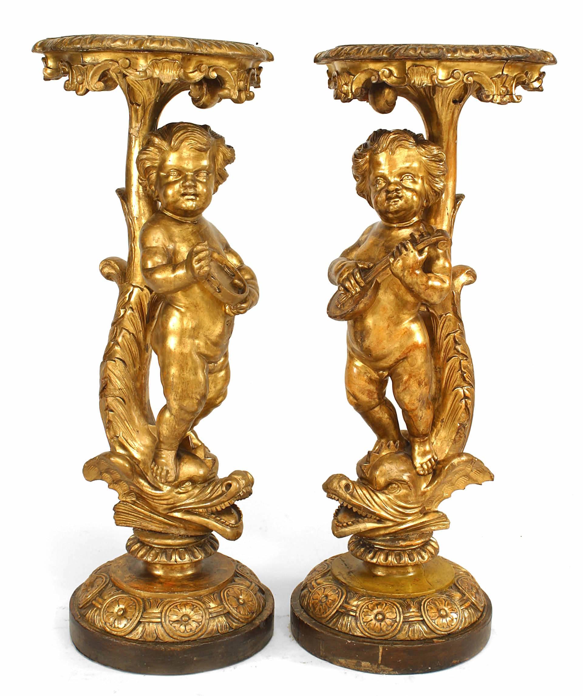 Zwei vergoldete Sockel im Stil von Louis XV (19. Jh.) mit Cherubfiguren, die Musikinstrumente spielen und auf Meerestieren stehen.
