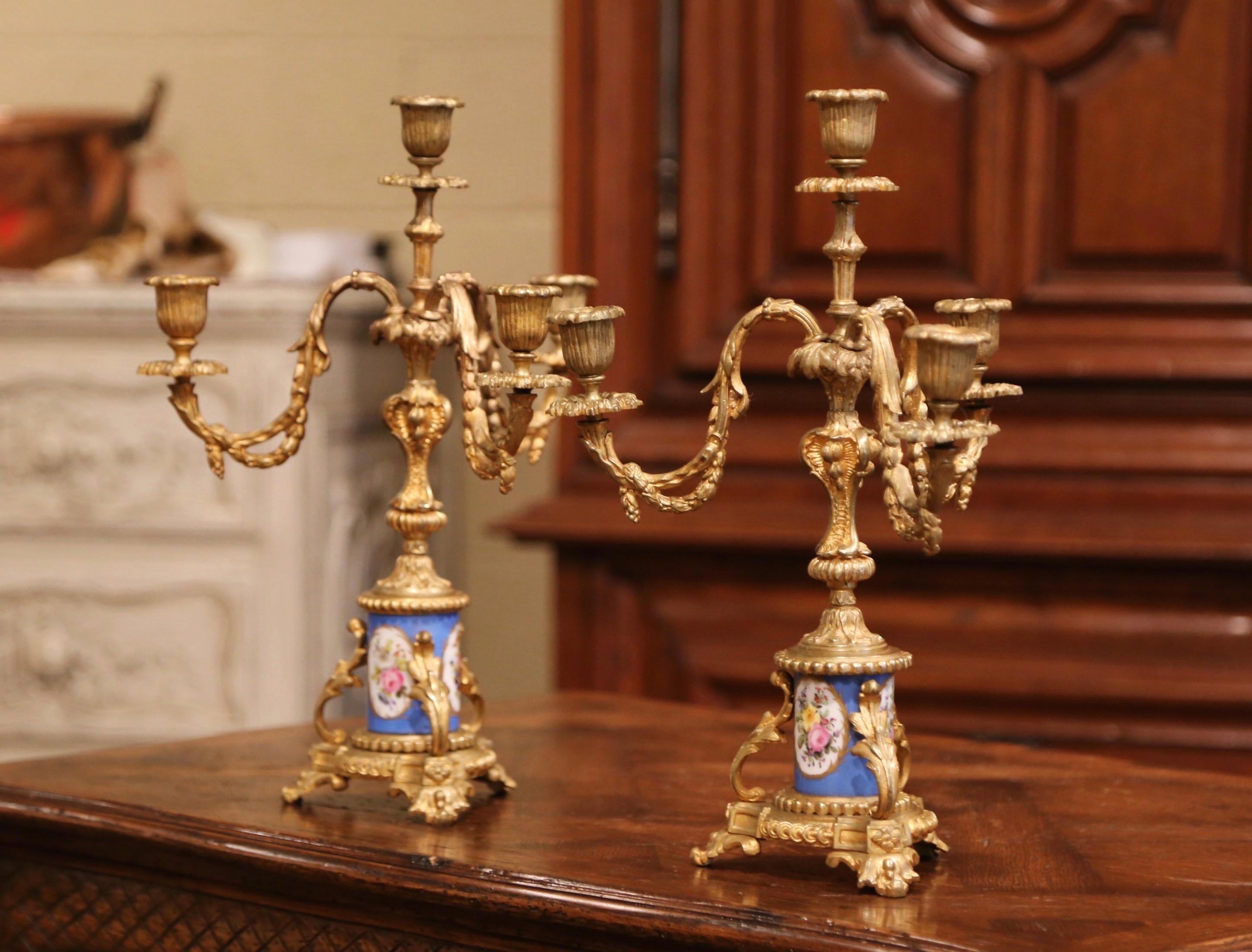 Decorate a dining room table or a mantel with this elegant pair of antique bronze candleholders. Crafted in France circa 1870, each candelabra stands on a tripod base with curved feet over a colorful hand painted porcelain stem decorated with floral