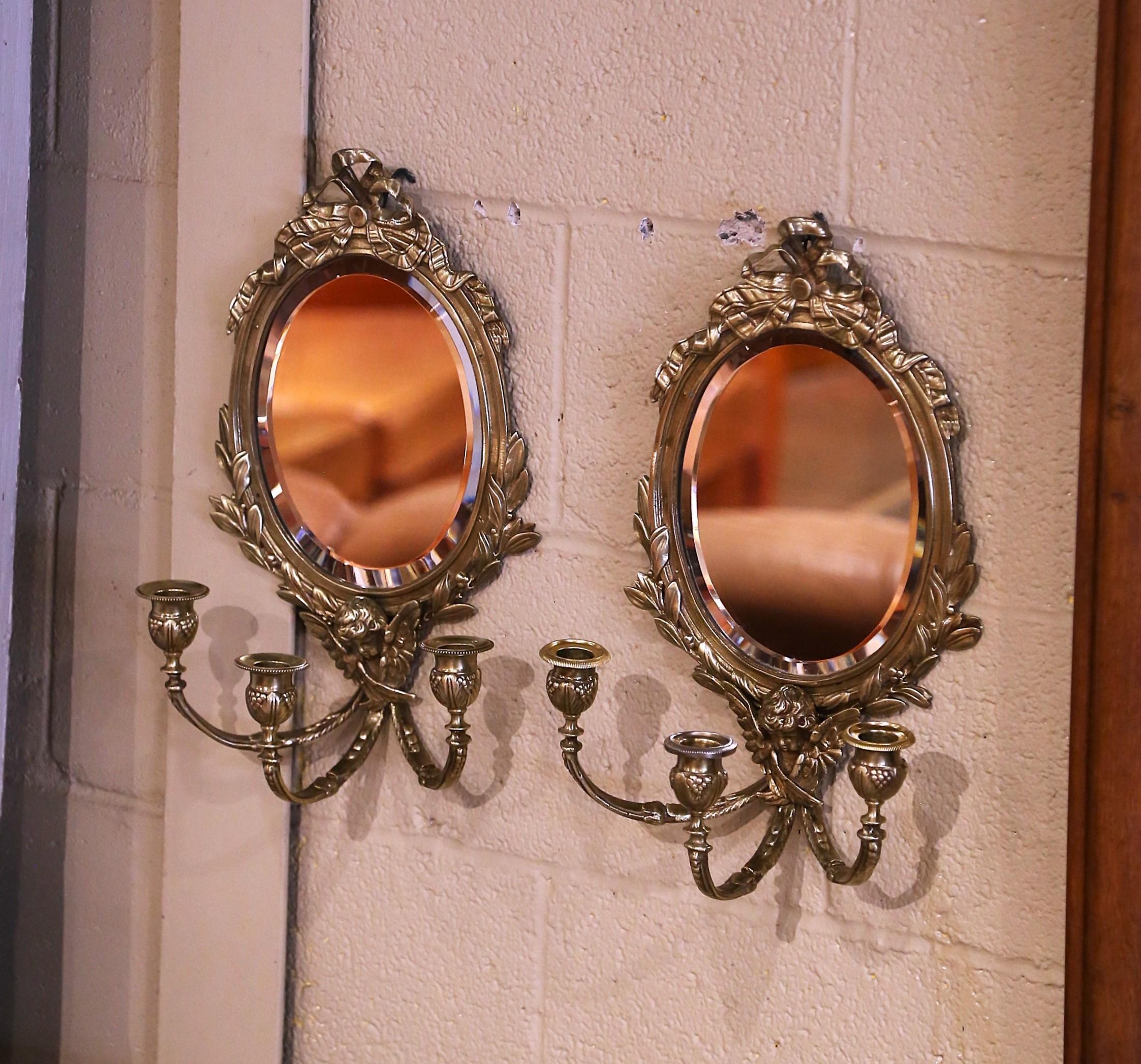 Ajoutez une touche d'élégance à une entrée avec cette paire frappante de miroirs muraux antiques. Fabriqué en France vers 1890, chaque miroir biseauté de forme ovale est enchâssé dans un cadre en bronze finement détaillé, couronné en haut par le