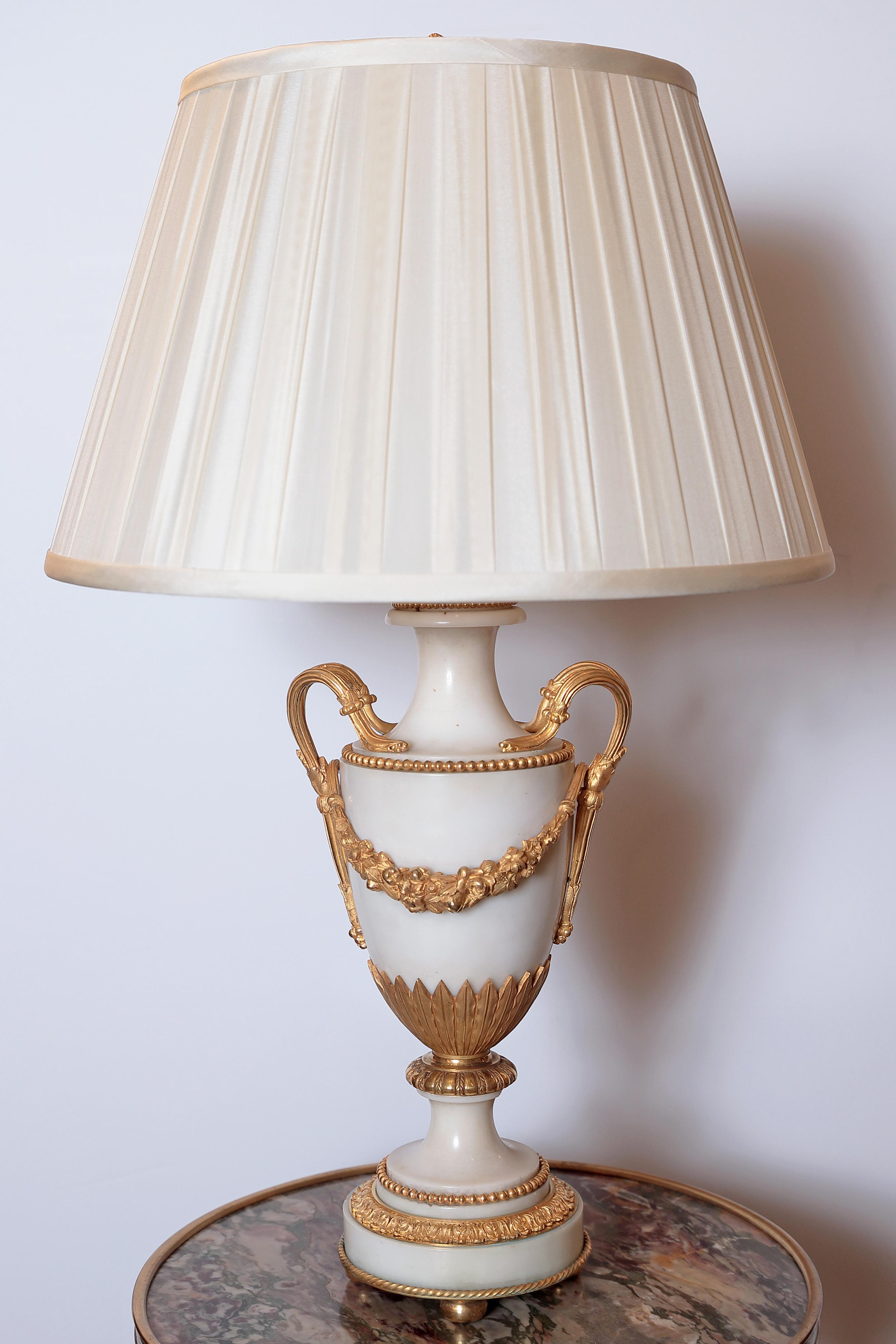A fine pair of French 19th century Louis XVI Carrara marble and gilt bronze urn lamps. Custom wiring and shades.