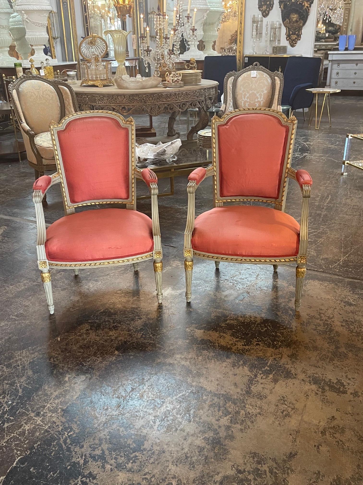 Lovely pair of 19th century French Louis XVI carved and painted armchairs. Beautifully carved and painted in green and gold. And the chairs are upholstered in a beautiful pink silk fabric. Gorgeous!