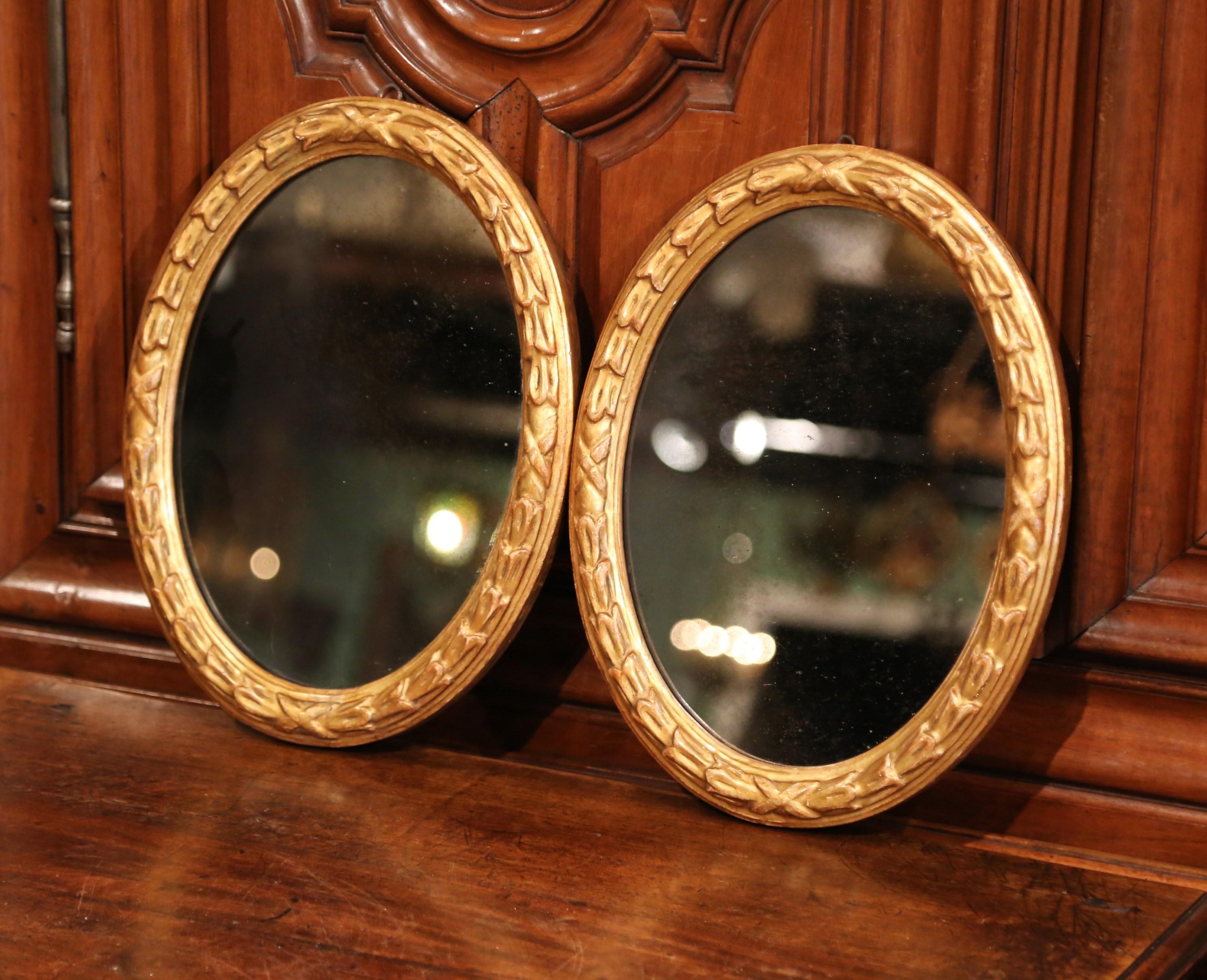 Decorate an entryway with this elegant pair of matching antique wall mirrors. Crafted in France circa 1880, each traditional, oval frame is hand carved with leaf decor and has a water gilt finish. Both mirrors are set with their original mercury