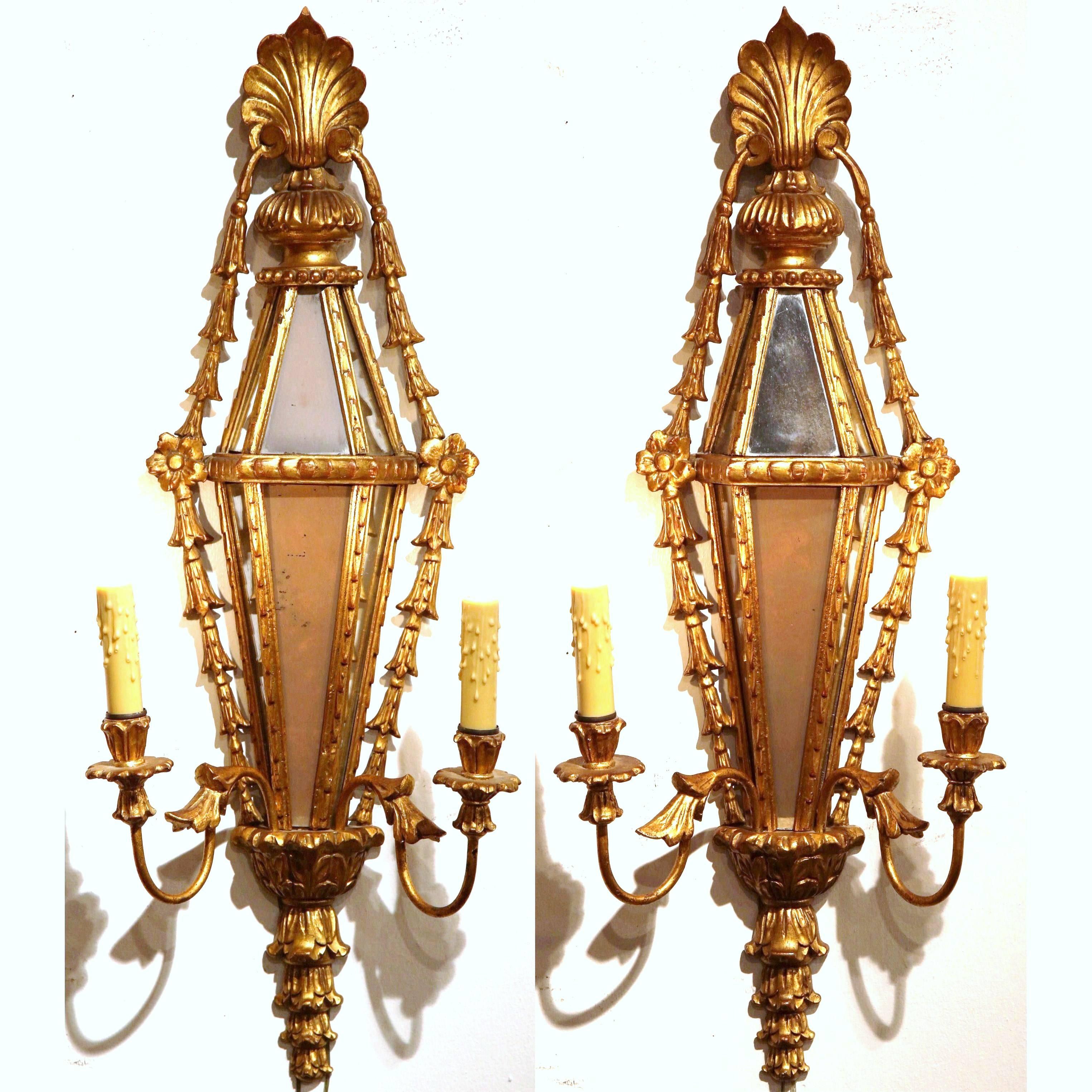 Add sophisticated lighting to the walls of your entryway or formal living room with this pair of elegant antique Louis XVI sconces. Sculpted in France, circa 1860, the two-light sconces have a beautiful gold leaf finish, embellished by three-side