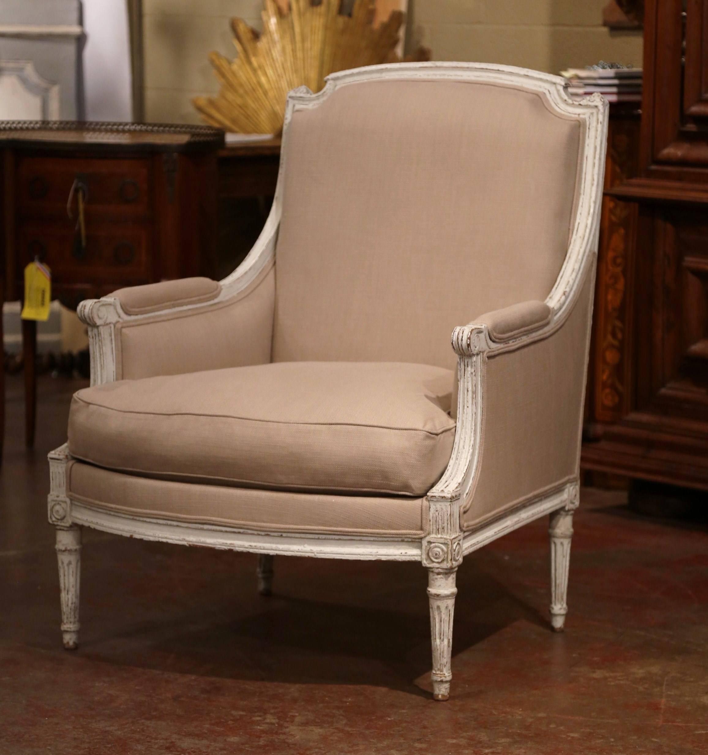 This elegant pair of antique armchairs was created in France, circa 1870. The large armchairs feature a carved frame with arched back, fluted and tapered legs embellished by square medallions at the shoulders. Both chairs with armrests and plush