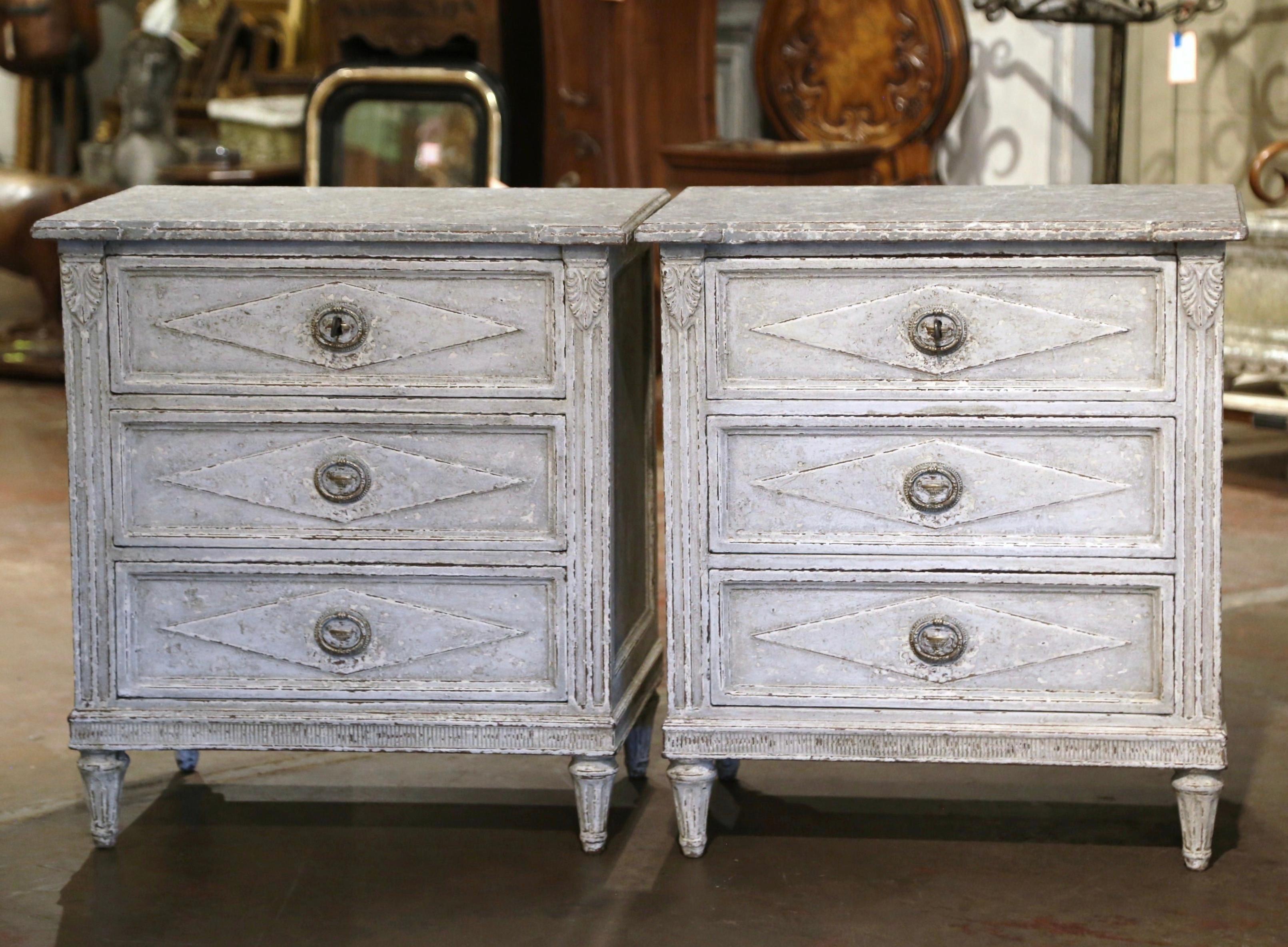 Complete your bedroom with this elegant pair of antique hand painted bedside cabinets. Crafted in France, circa 1880, each commode stands on tapered and fluted legs over a straight apron decorated with geometric motif. Each chest features three
