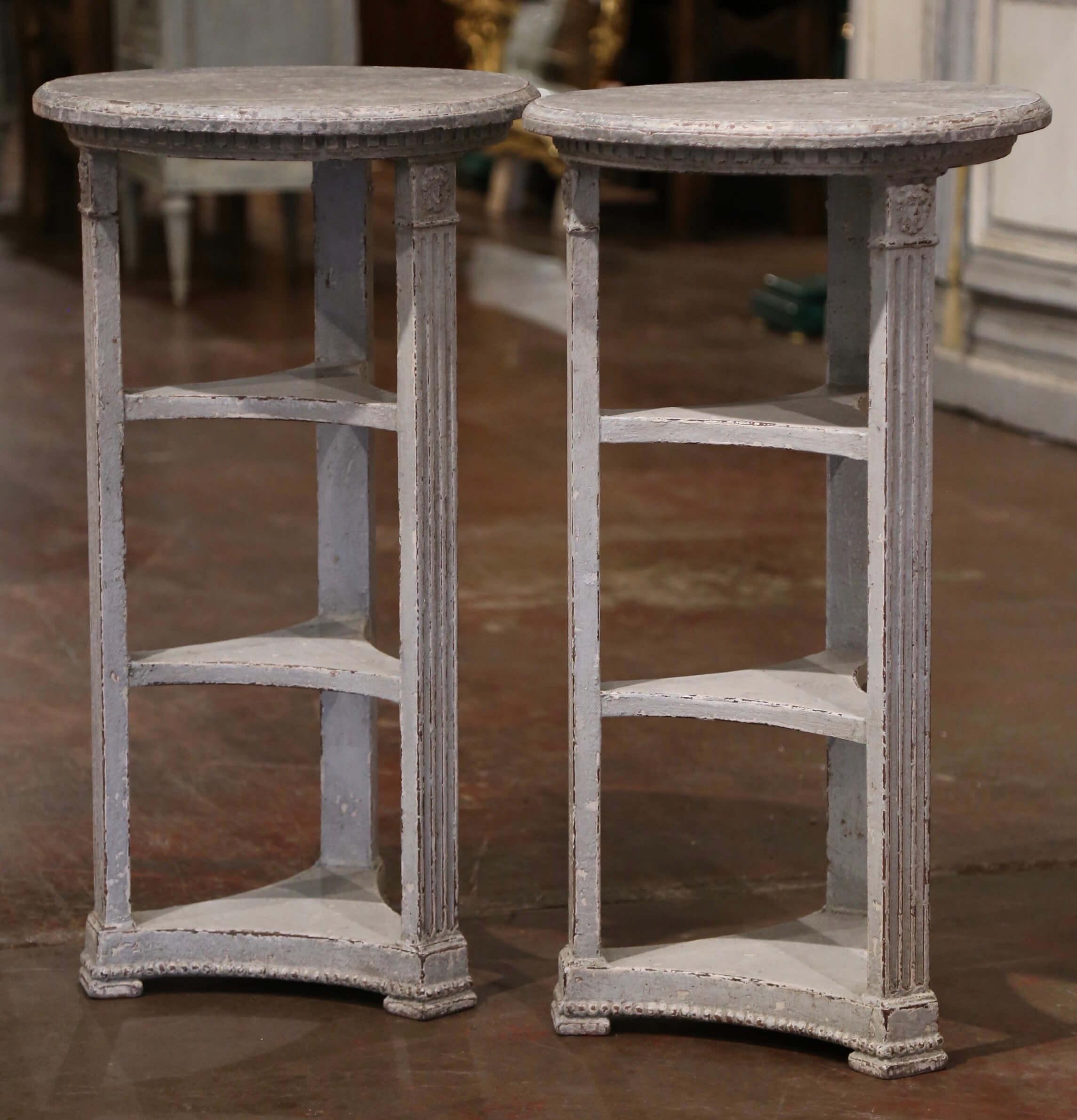 These elegant antique side tables were created in France, circa 1880. Each occasional table stands on three hand carved spline legs embellished with carved female head medallions at the shoulder and connected with triple tier shelves. The top is